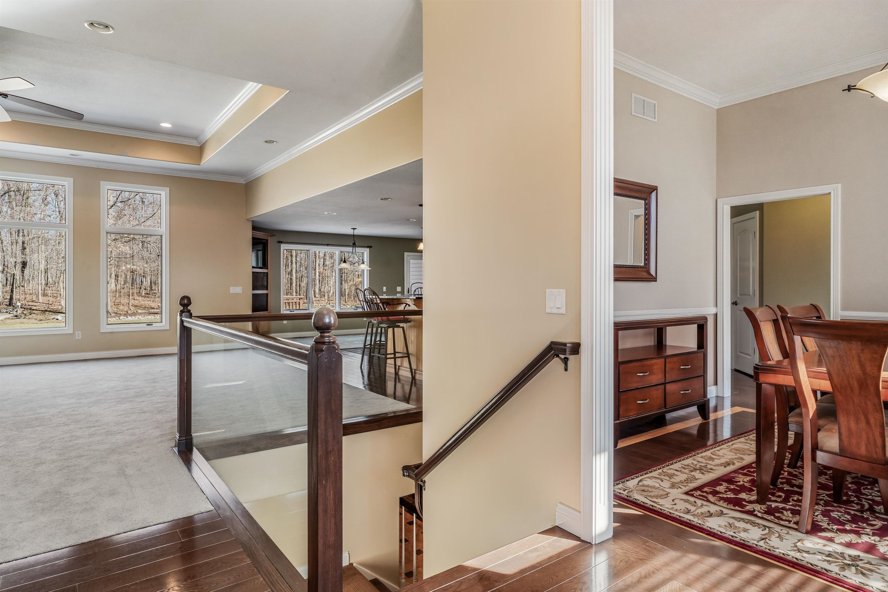 Corridor featuring an upstairs landing, ornamental molding, dark wood-style flooring, dark carpet, and a raised ceiling