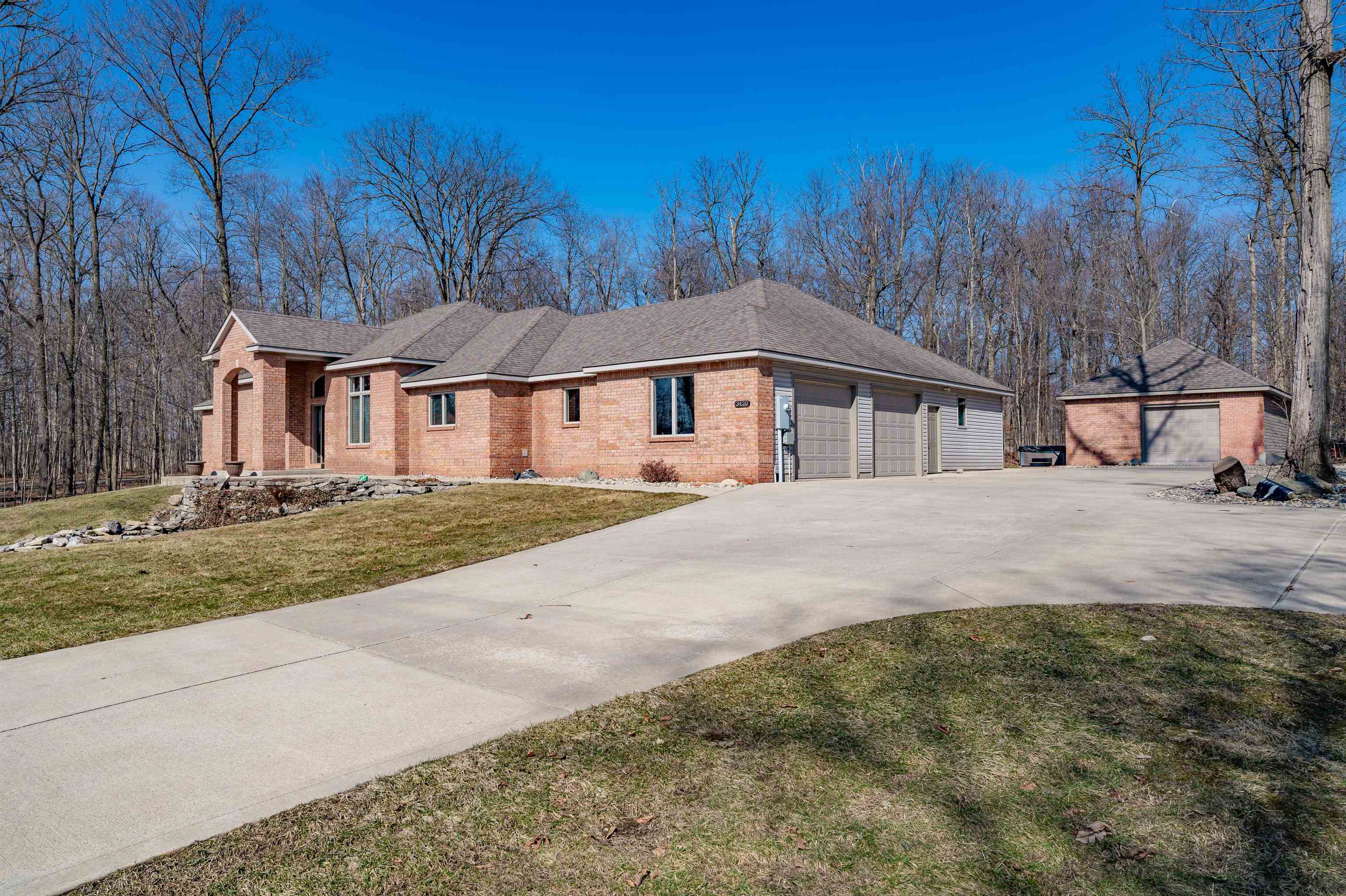 Ranch-style home featuring brick siding, a front yard, concrete driveway, a shingled roof, and a garage