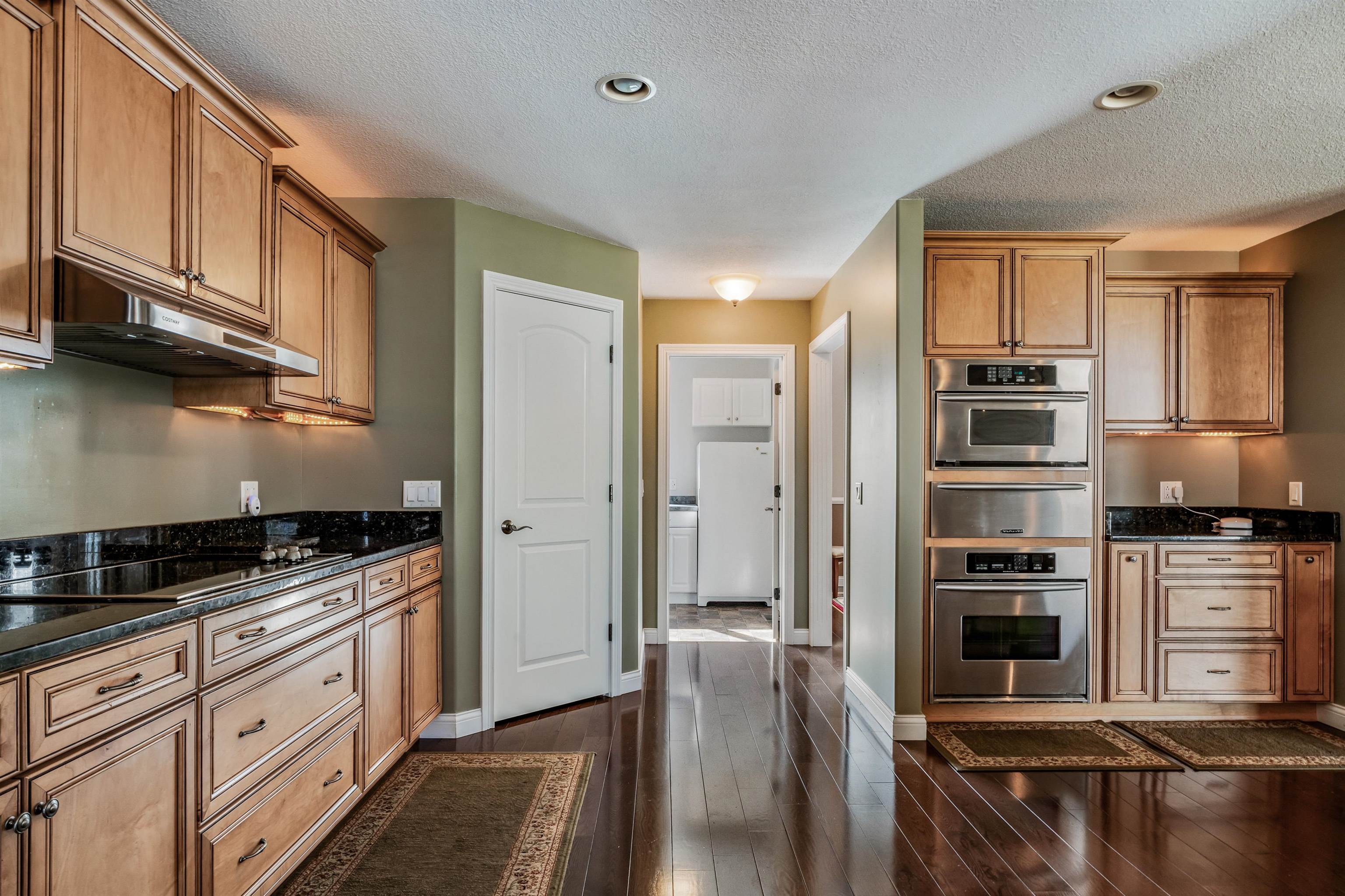 Kitchen featuring stainless steel oven, a warming drawer, dark stone counters, freestanding refrigerator, and a textured ceiling