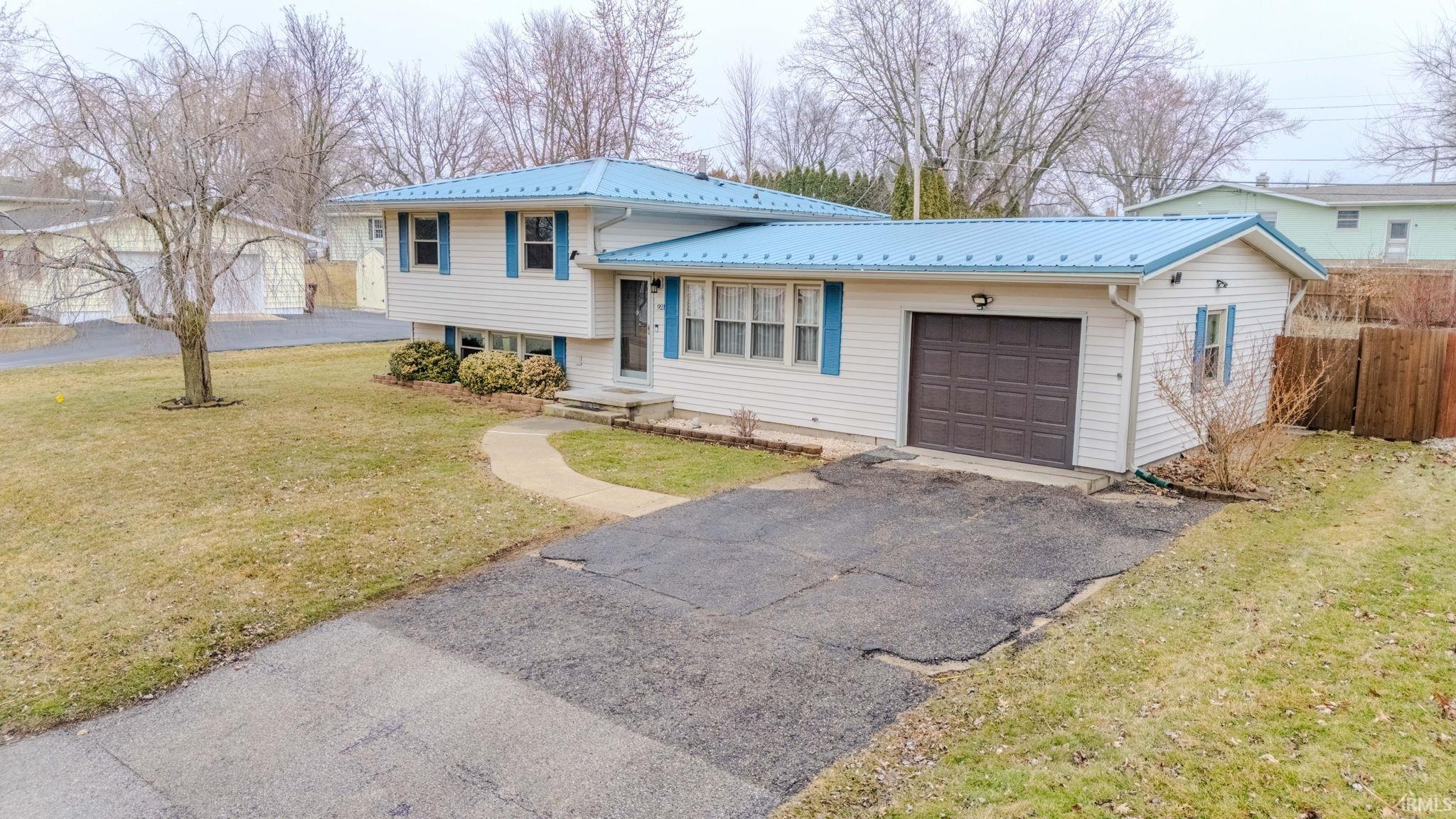 Tri-level home with an attached garage, asphalt driveway, and a metal roof