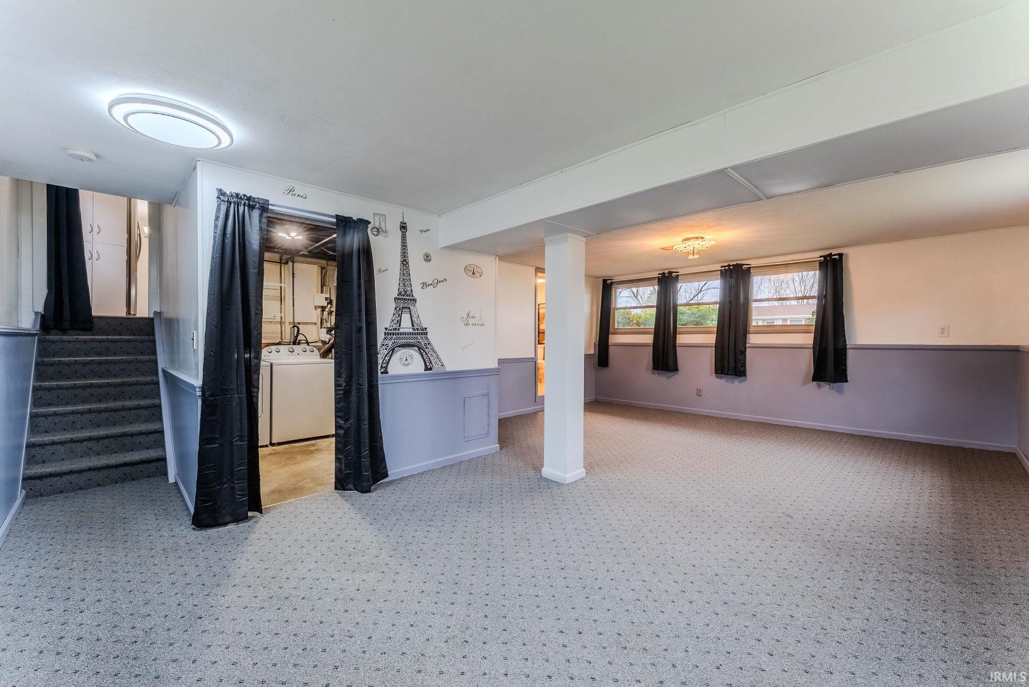 Below grade area with wainscoting, light colored carpet, and washer / clothes dryer