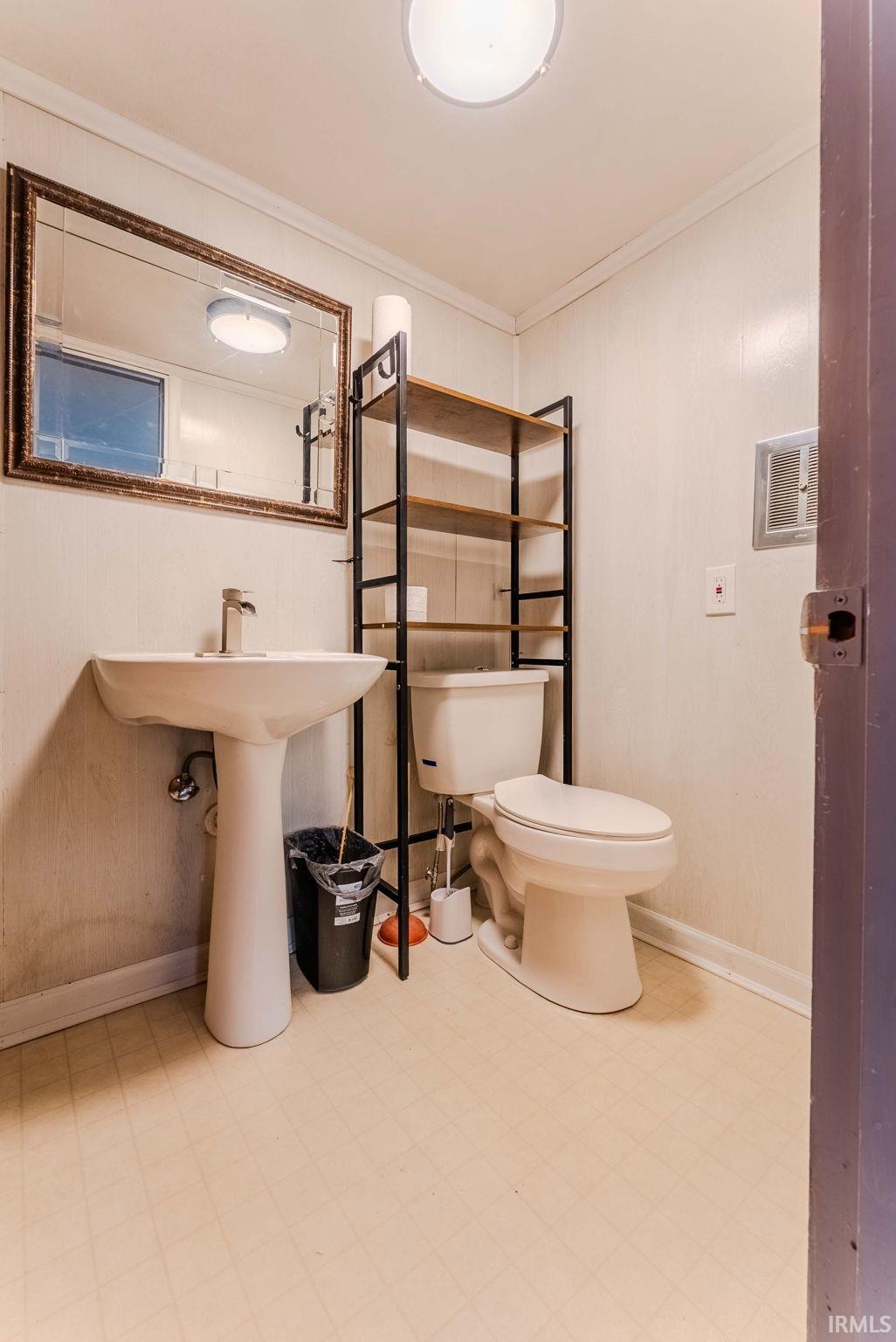 Half bath with light floors and ornamental molding