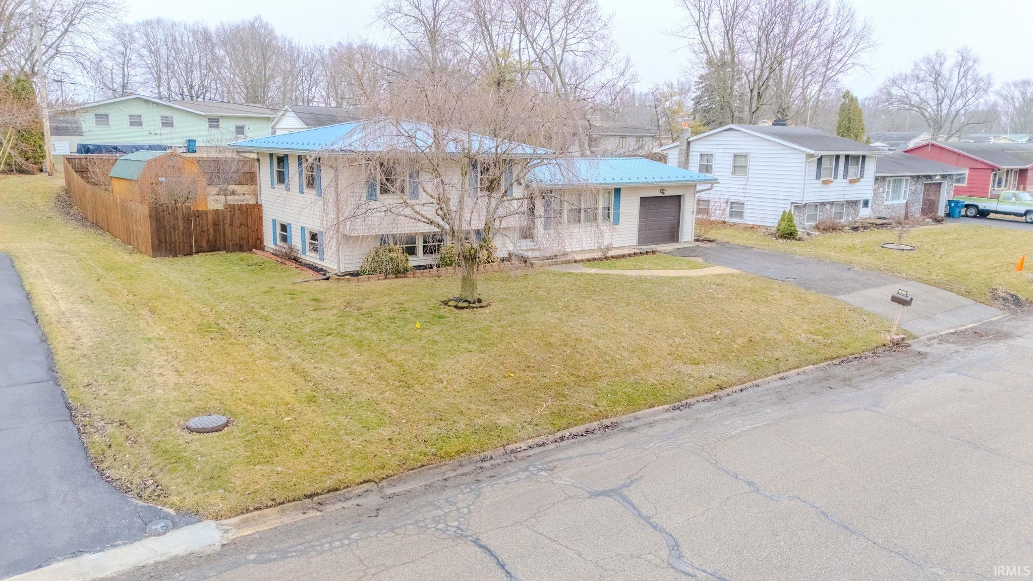 View of front of home featuring asphalt driveway, a front yard, a residential view, and a garage