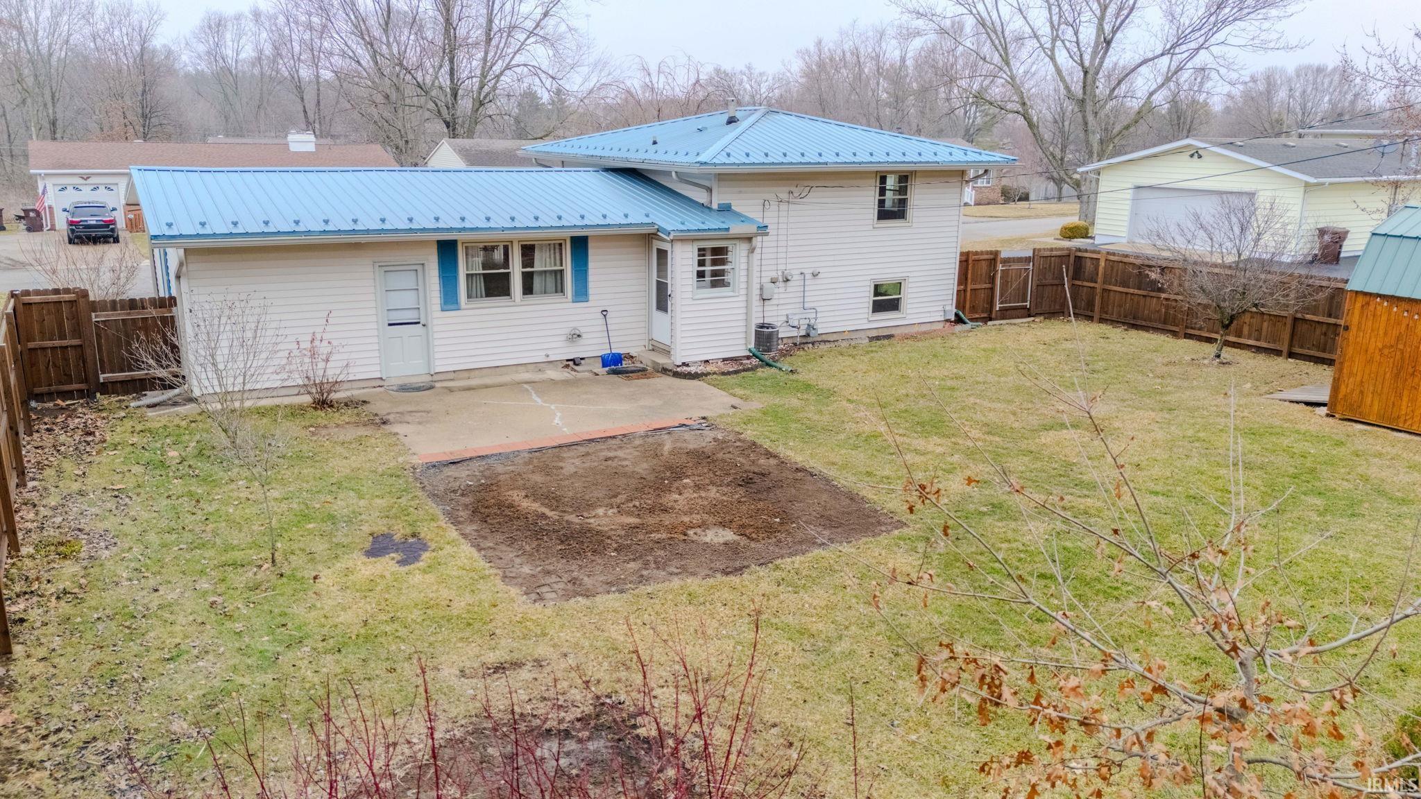 Rear view of house featuring a metal roof, a patio, and a fenced backyard