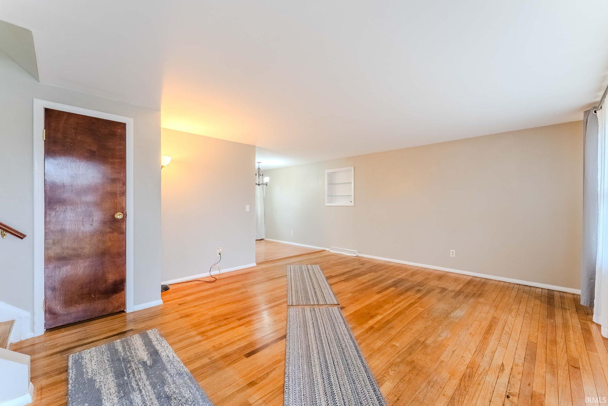 Unfurnished living room with light wood finished floors and hanging lights