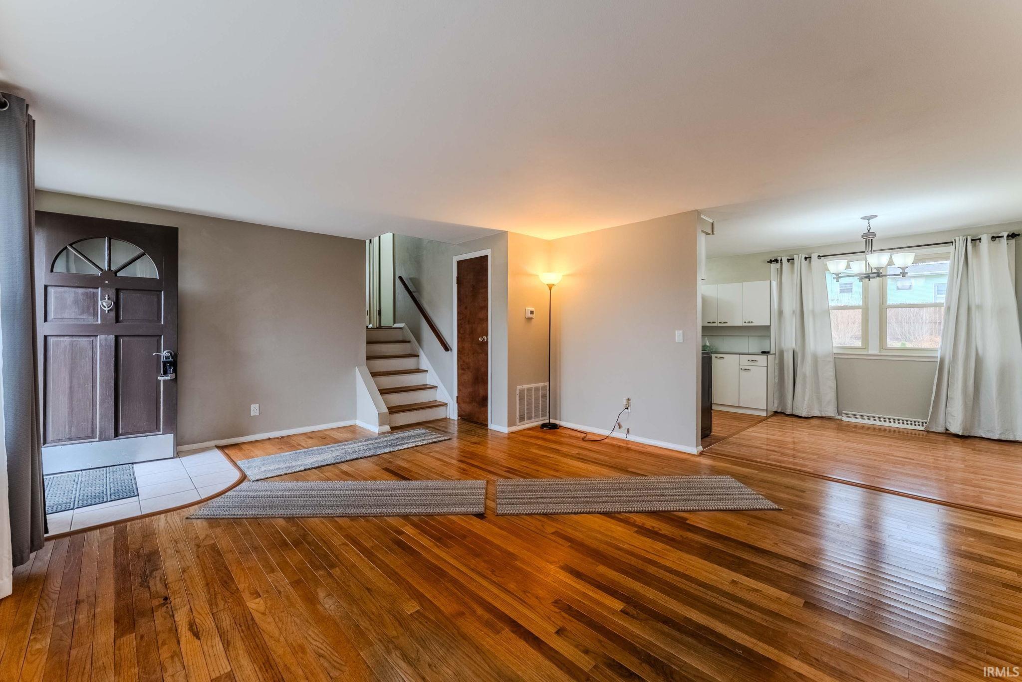 Unfurnished living room with light wood-type flooring and suspended lighting
