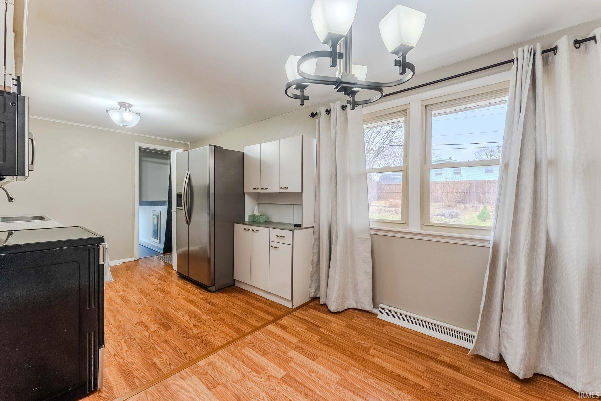 Kitchen featuring stainless steel fridge, white cabinetry, light wood-style floors, and a baseboard radiator