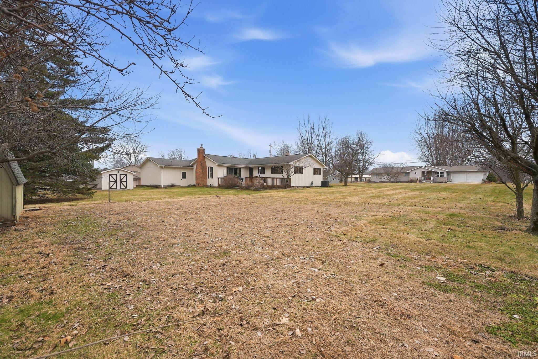 Rear view of property featuring a chimney, a shed, and a lawn