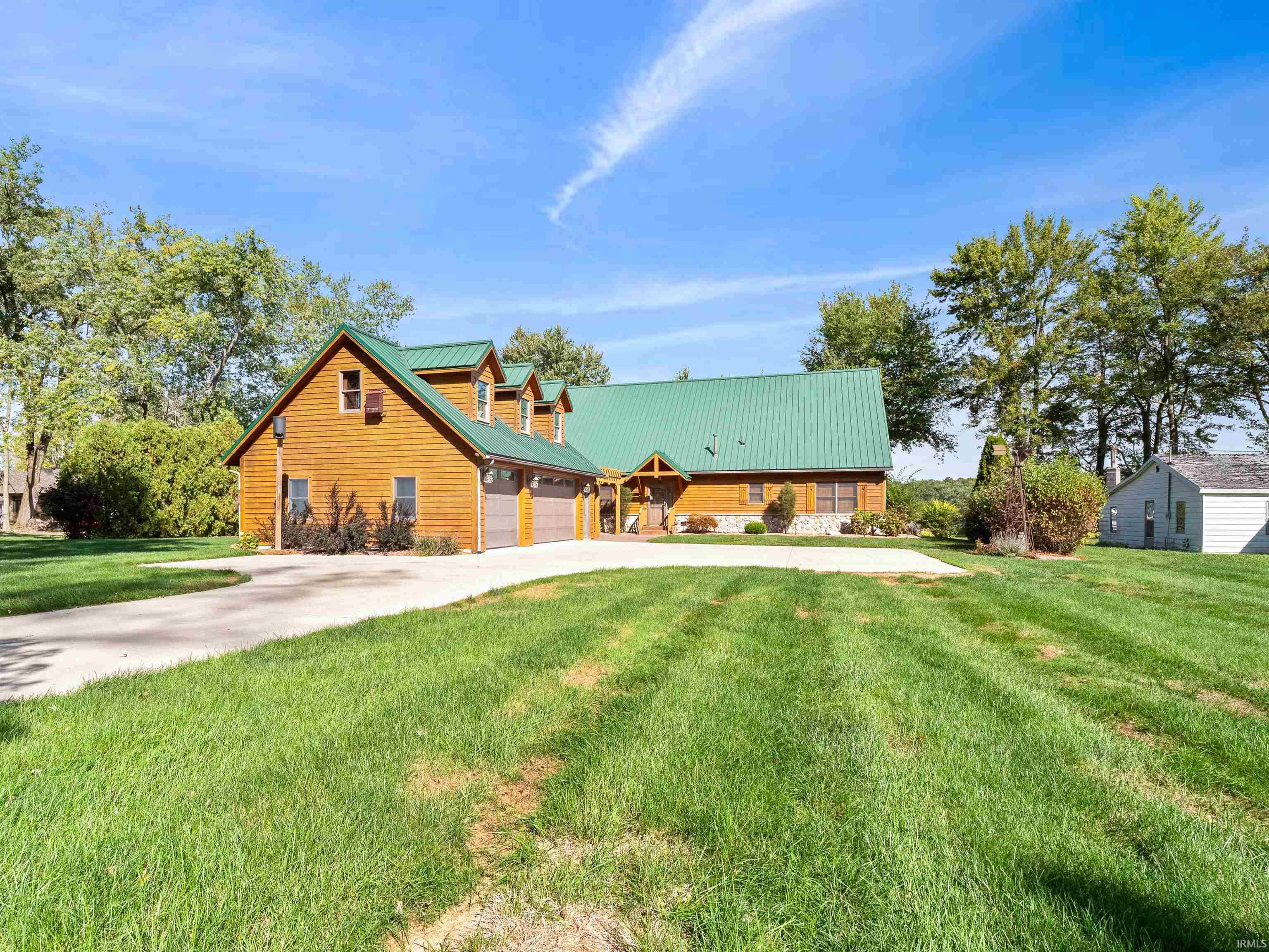 View of front of property with a front yard, concrete driveway, a metal roof, and an attached garage