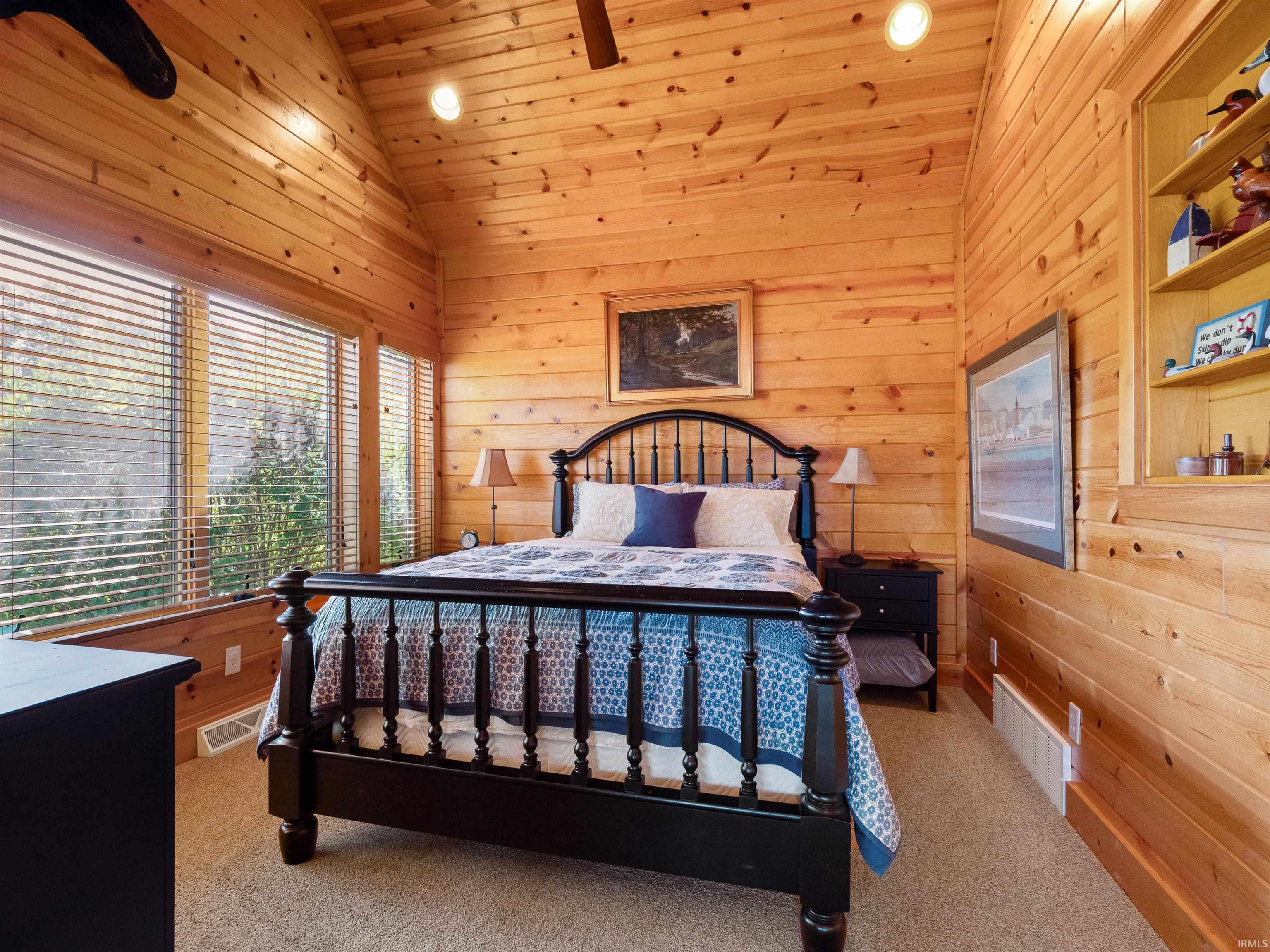 Bedroom with wooden walls, carpet flooring, and a vaulted wood ceiling