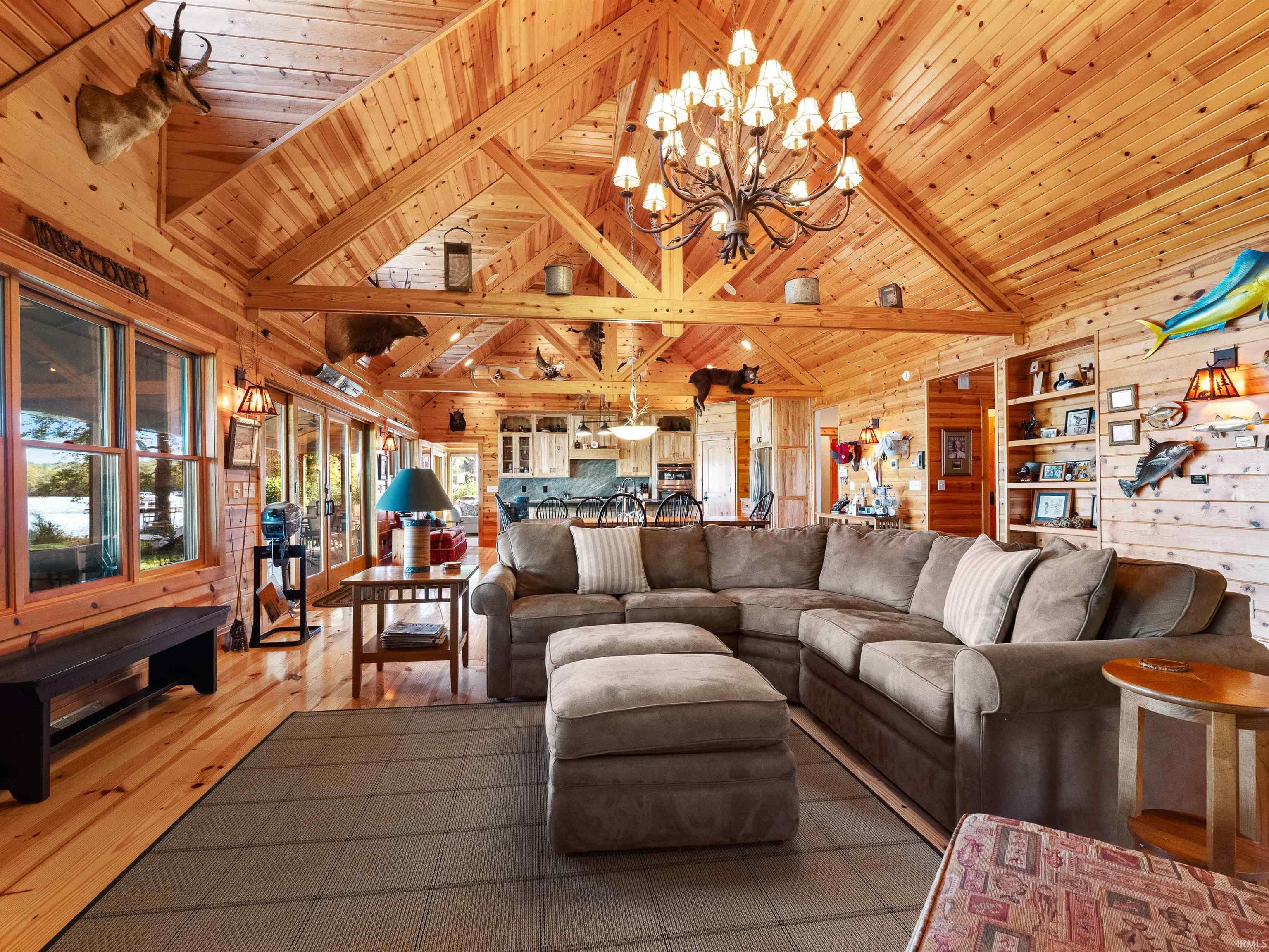 Living area featuring wooden walls, hardwood / wood-style flooring, suspended lighting, and a high wood beamed ceiling