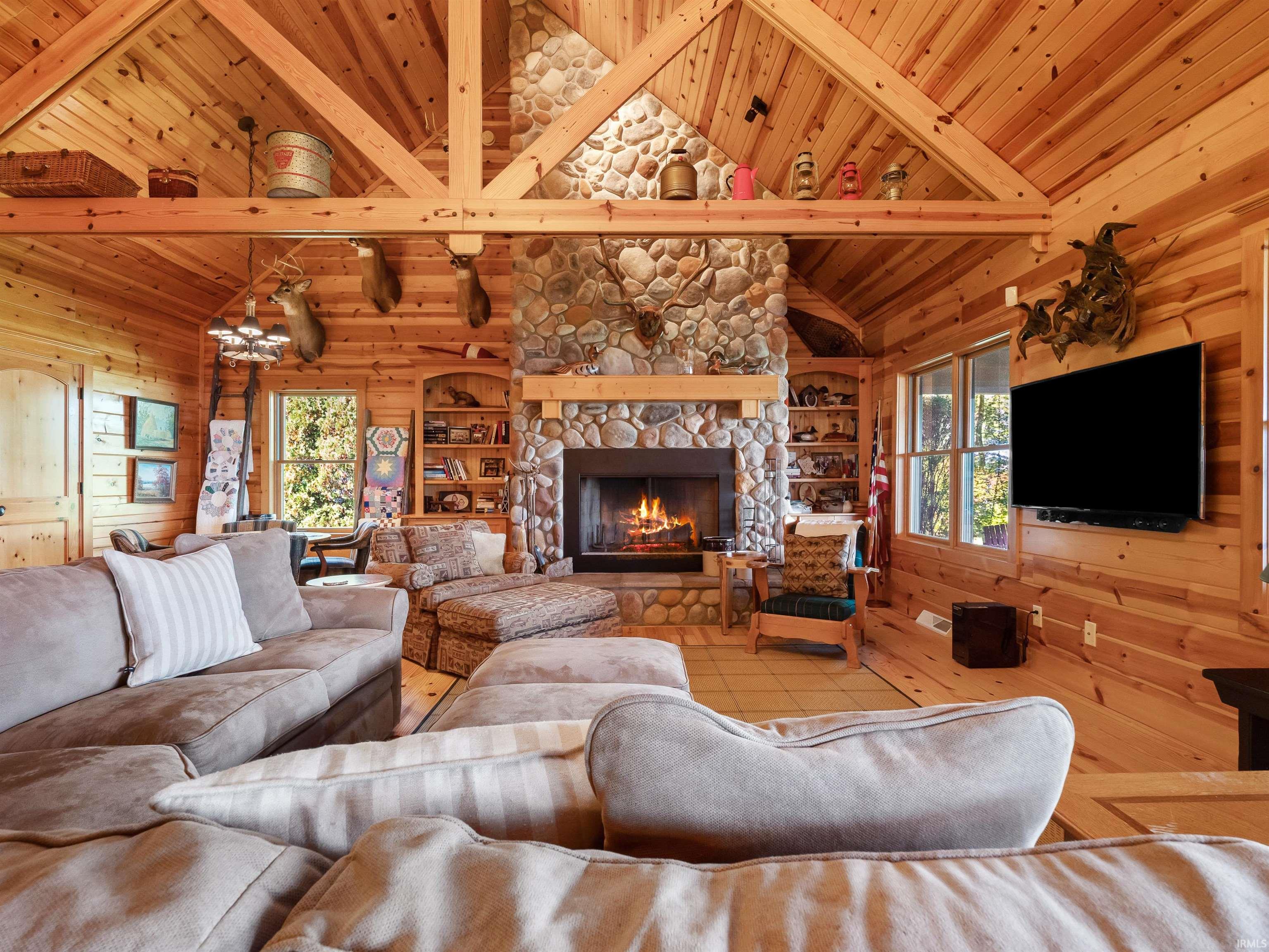 Tiled living area with wooden walls, a fireplace, and a vaulted wooden ceiling