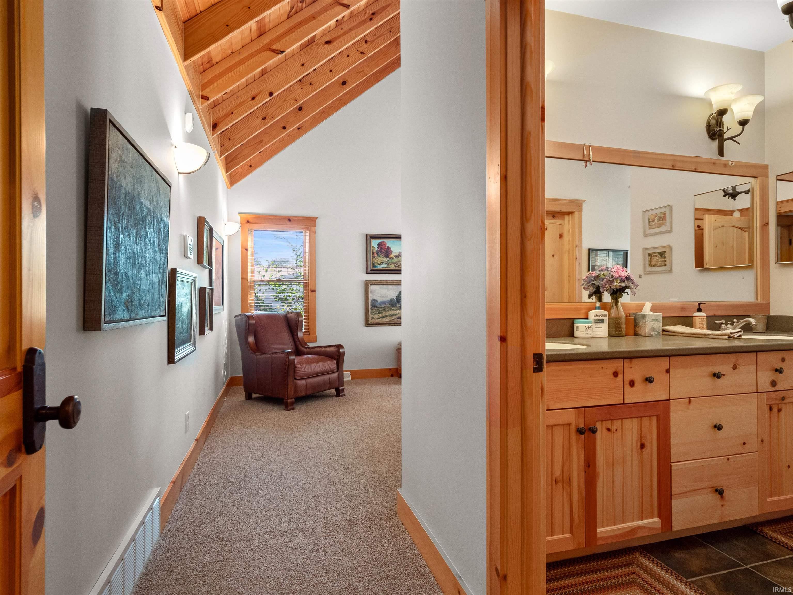 Hallway with dark colored carpet and a vaulted wooden ceiling