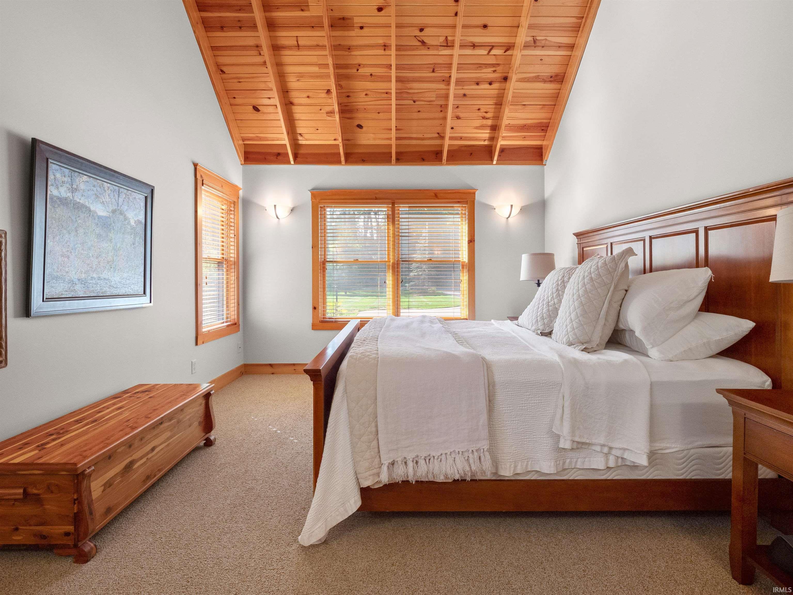 Bedroom featuring wood ceiling, lofted ceiling with beams, and carpet