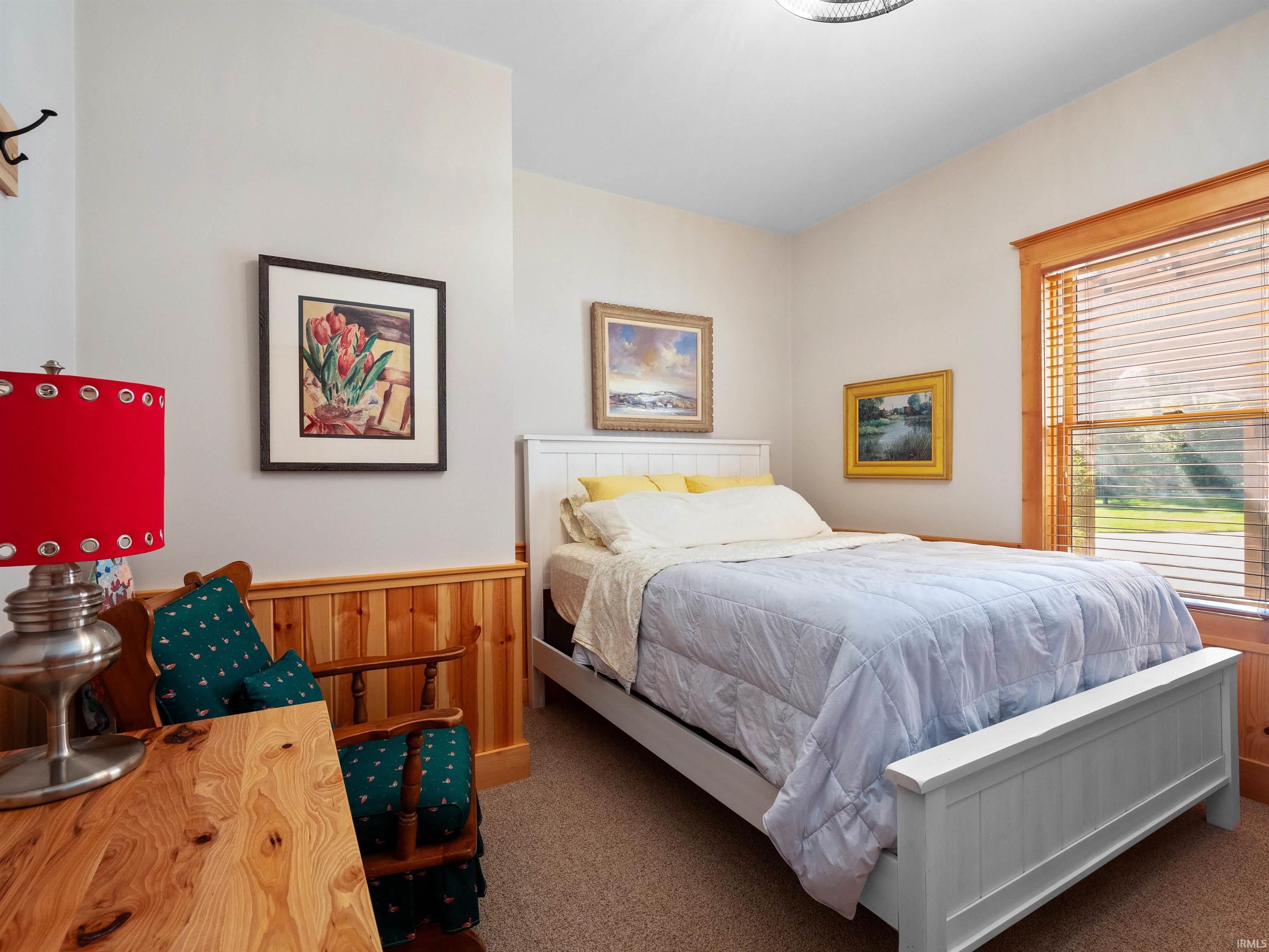 Bedroom with wooden walls, a wainscoted wall, and carpet flooring