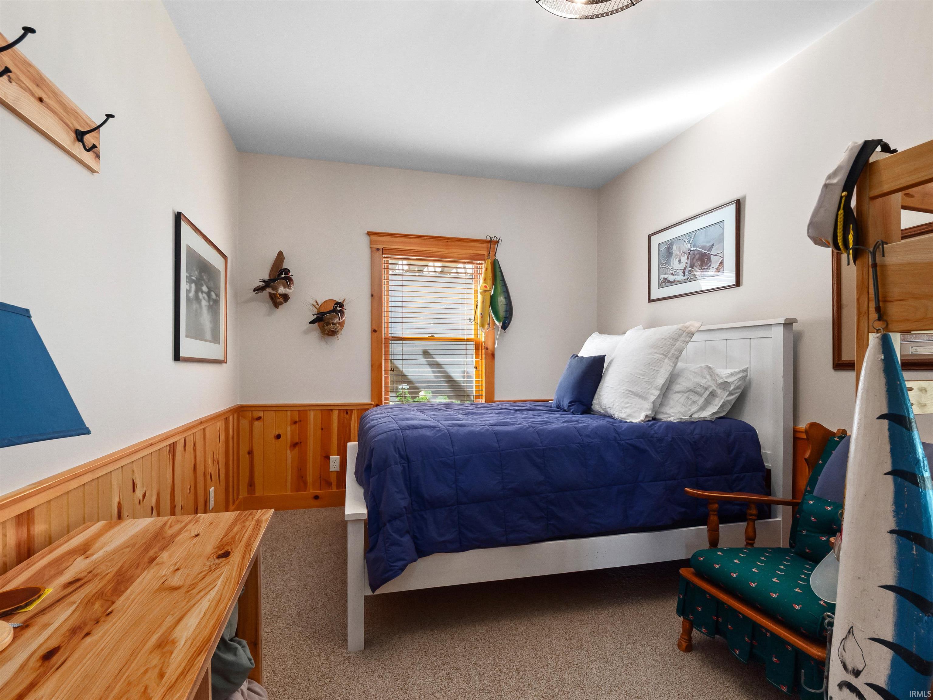 Carpeted bedroom with a wainscoted wall and wooden walls