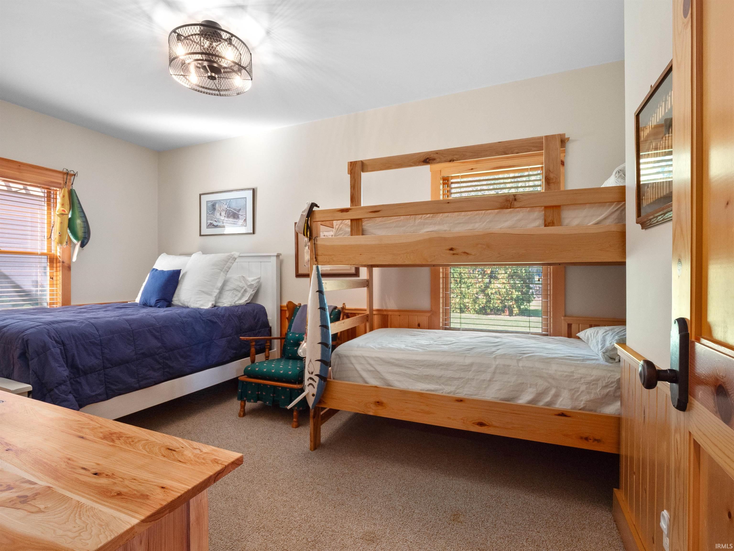 Bedroom with light colored carpet and multiple windows