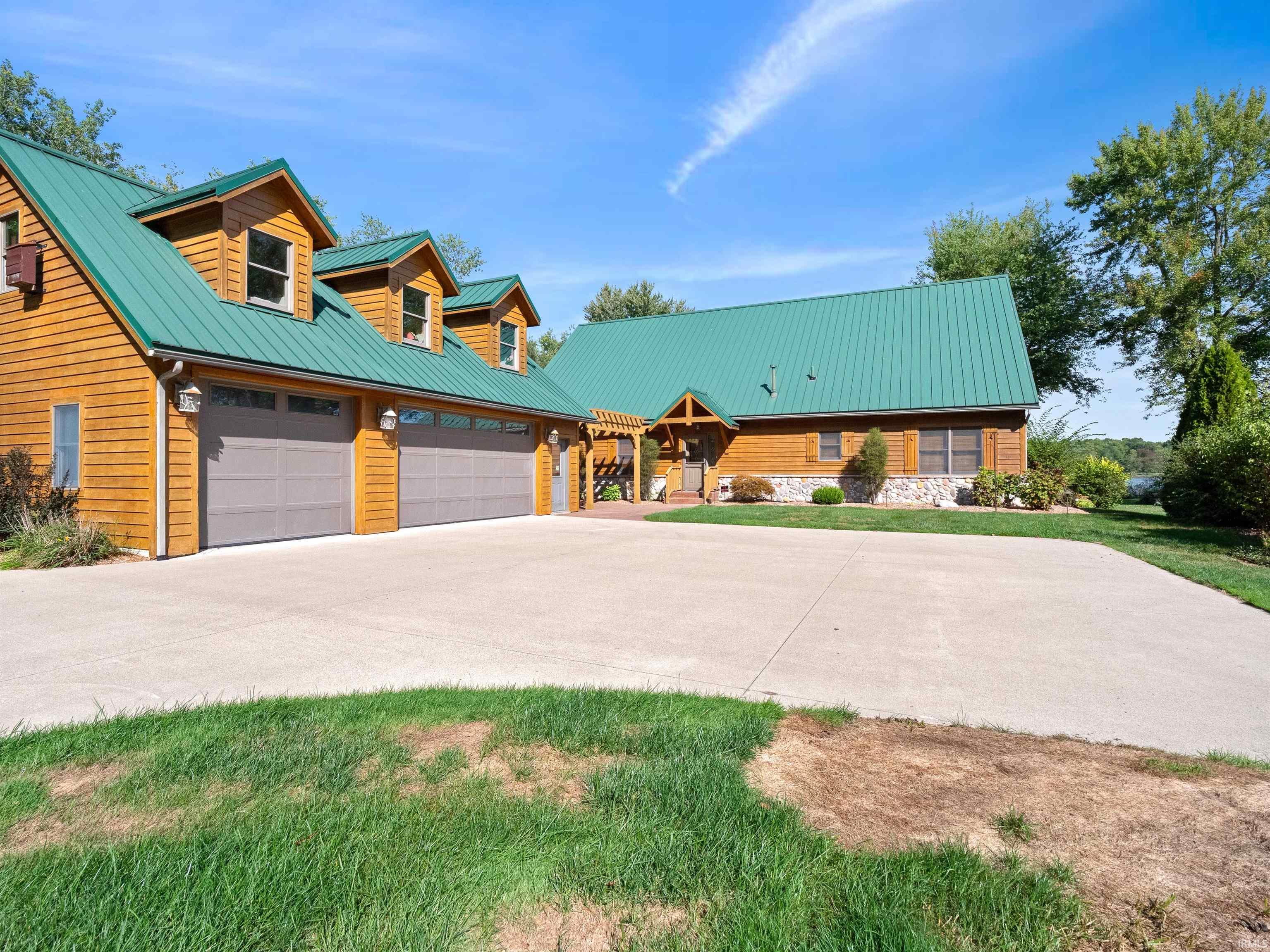 View of front of property featuring driveway, an attached garage, and a metal roof