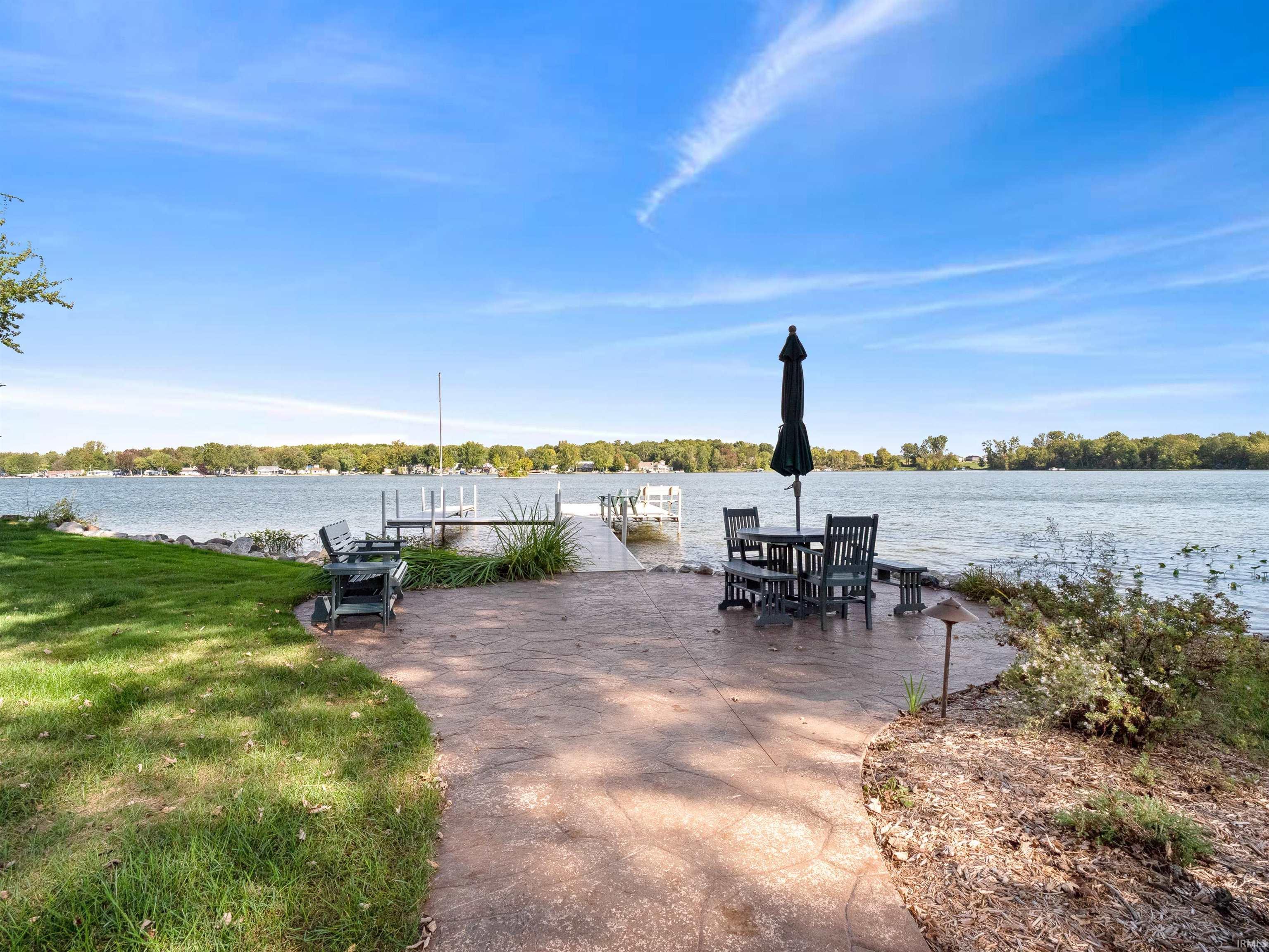 Dock featuring a water view, a patio area, and a lawn