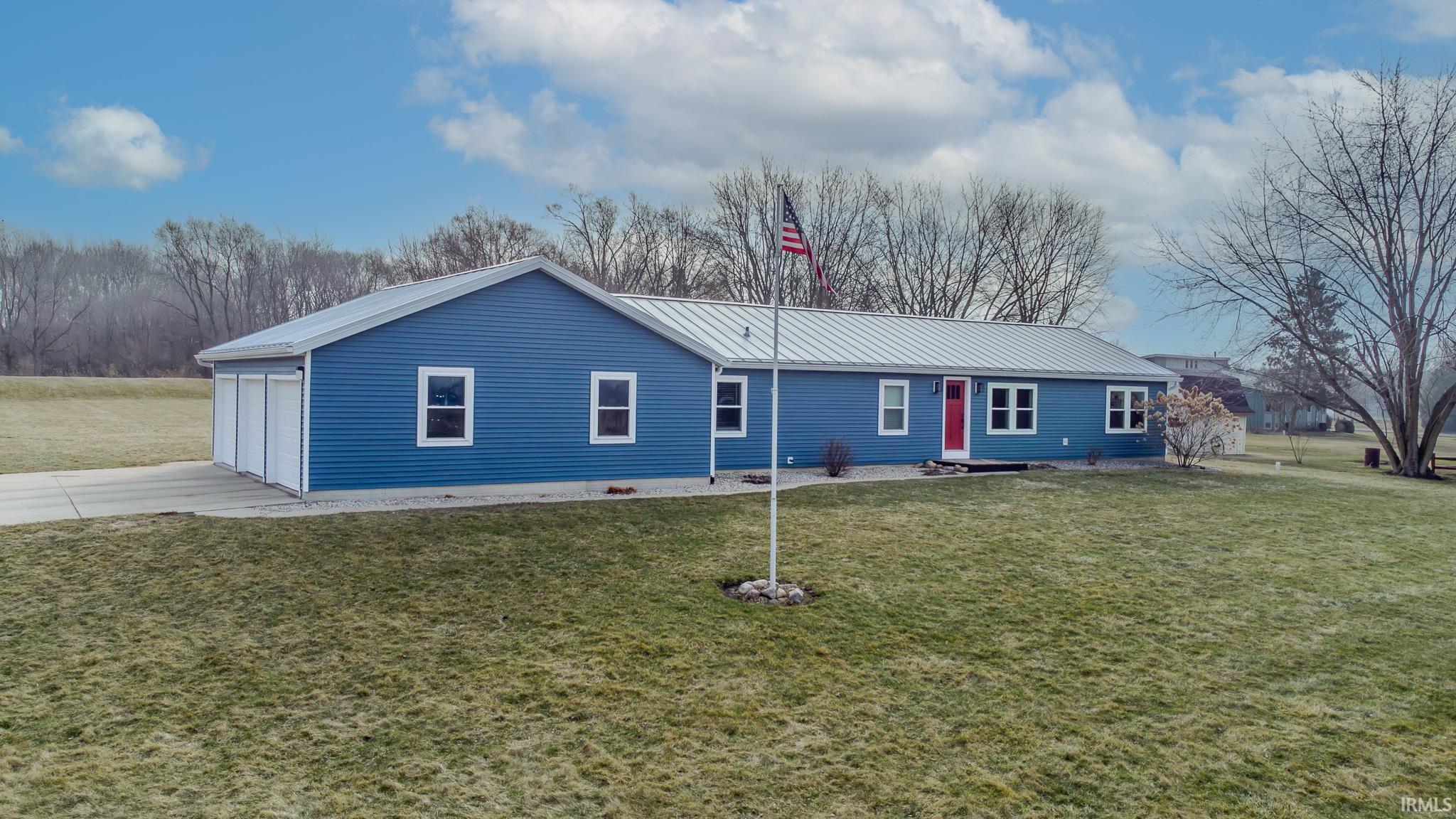 View of front of home featuring a front lawn, a metal roof, concrete driveway, and a garage