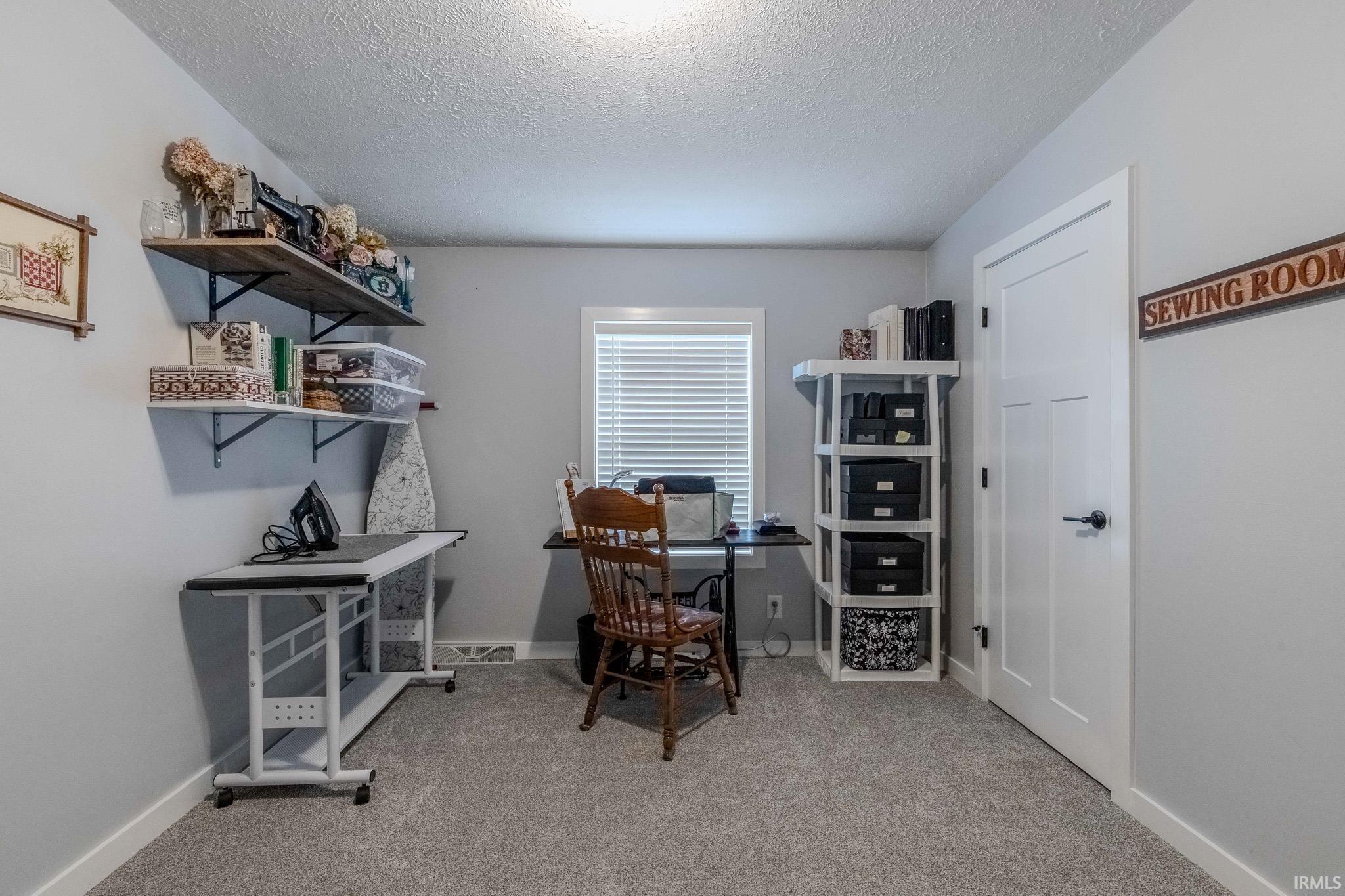 Office area featuring a textured ceiling and light carpet