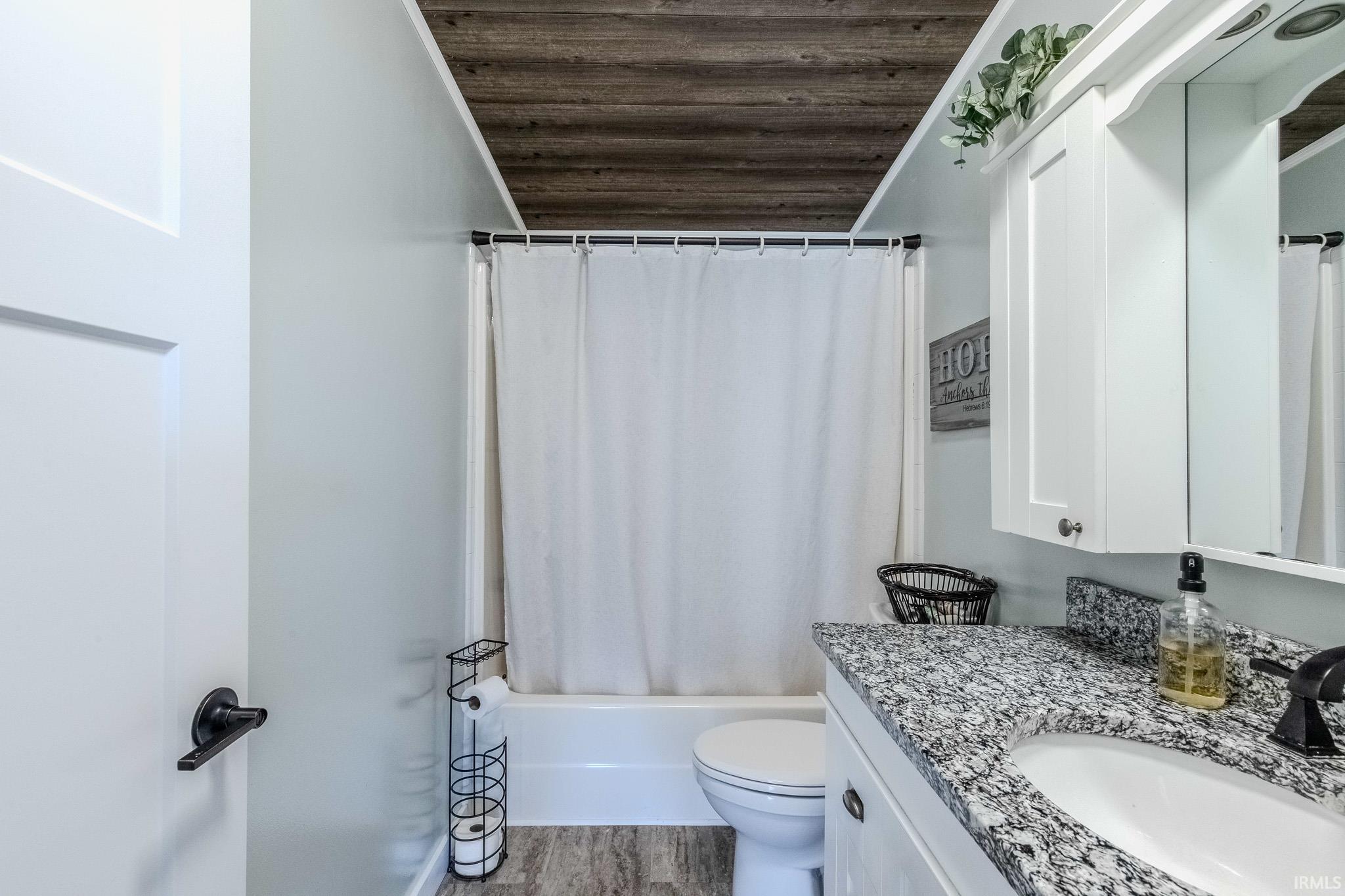 Full bathroom with vanity, wood ceiling, shower / tub combo, and light wood-style floors