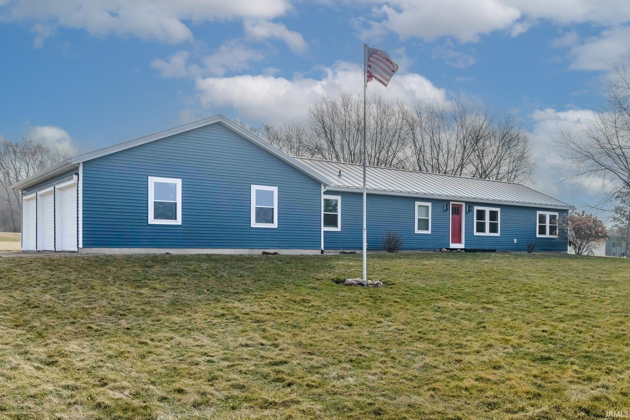 View of front of home with a metal roof and a front yard