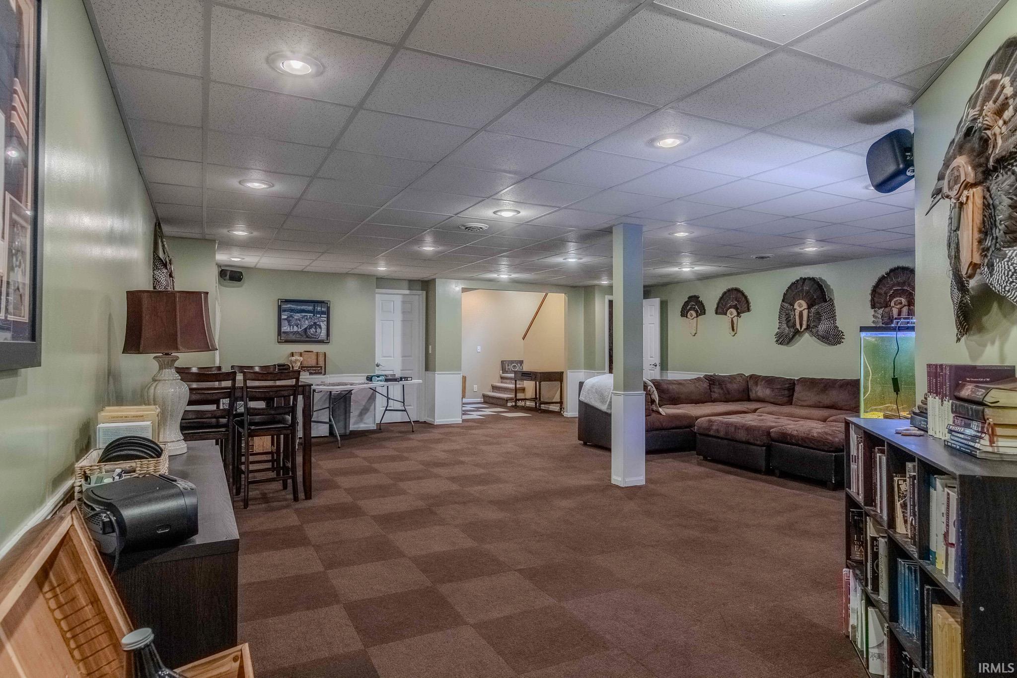 Living area with a paneled ceiling, dark colored carpet, and recessed lighting