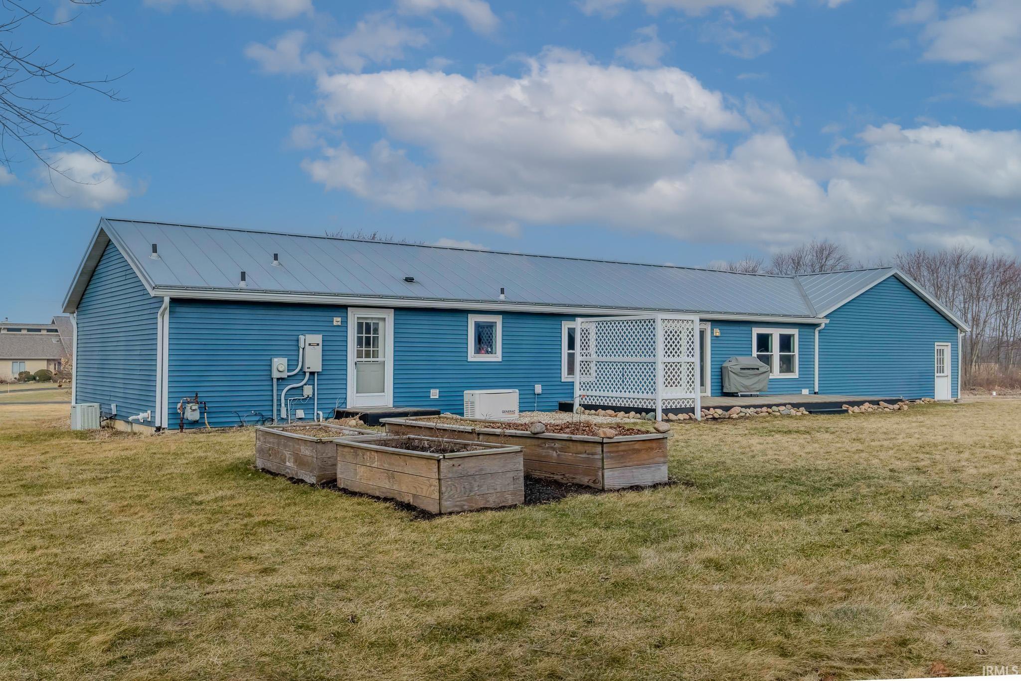 Back of property with a vegetable garden, a yard, and a metal roof