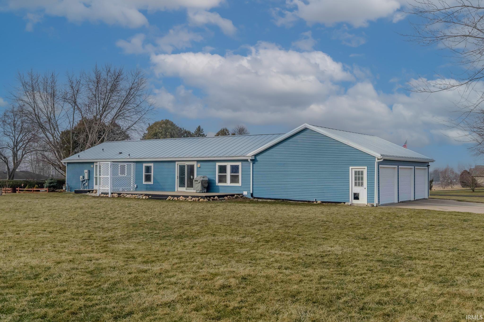 Single story home with a front yard, a metal roof, and driveway