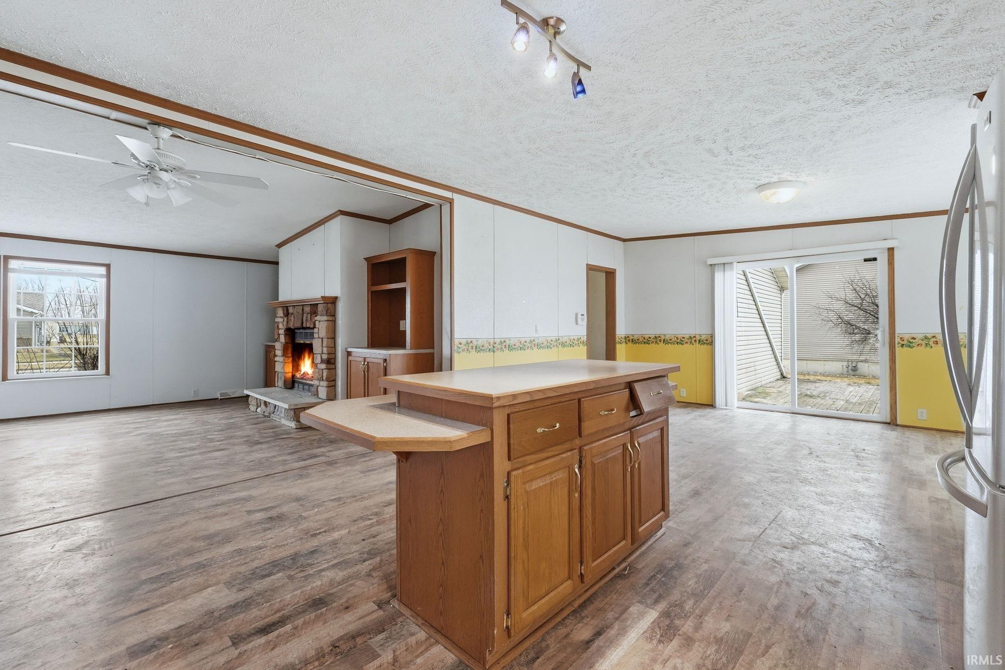 Kitchen featuring wood finish cabinets, ornamental molding, light countertops, open floor plan, and freestanding refrigerator