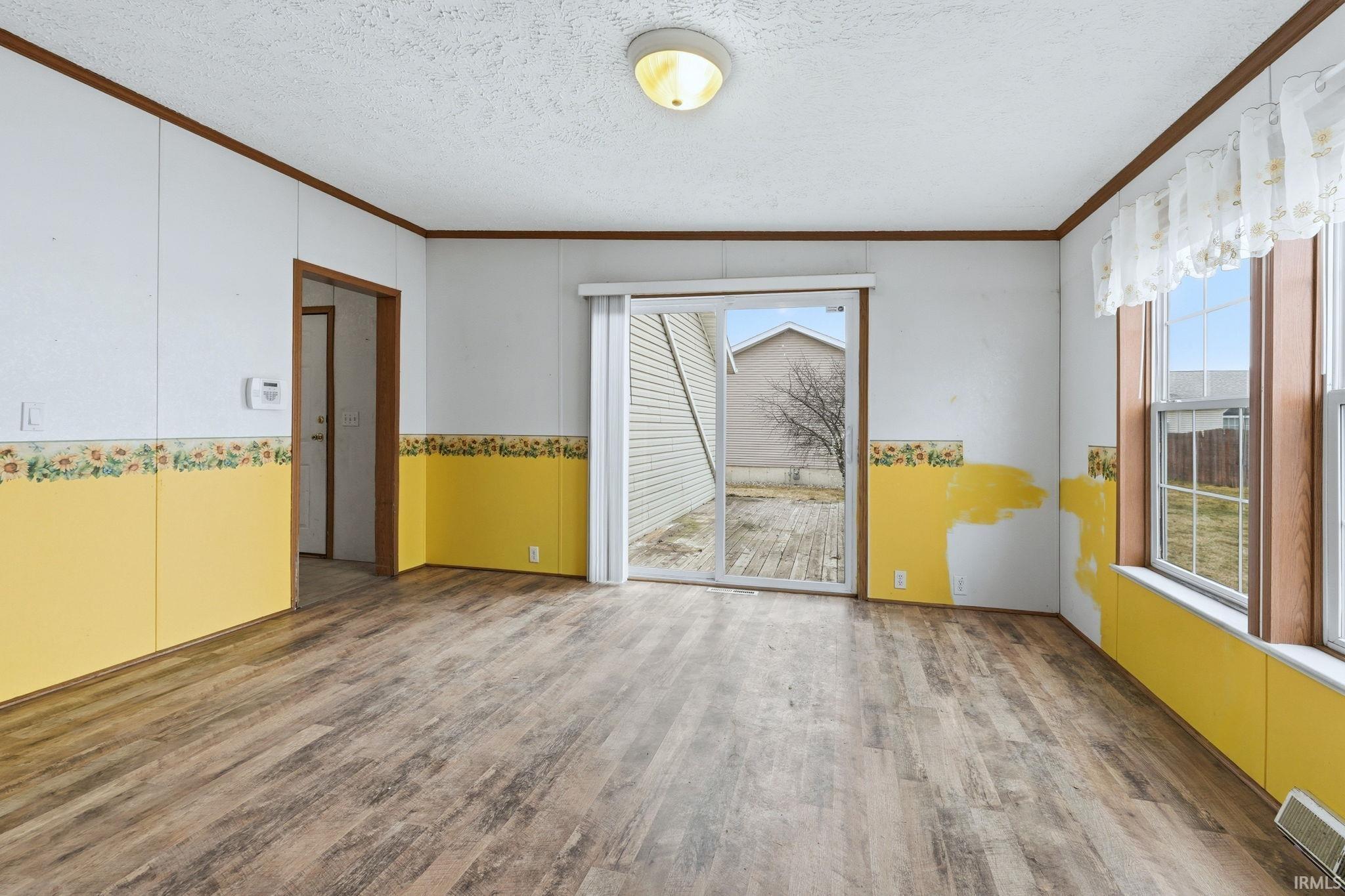 Unfurnished room with a textured ceiling, ornamental molding, and light wood-type flooring