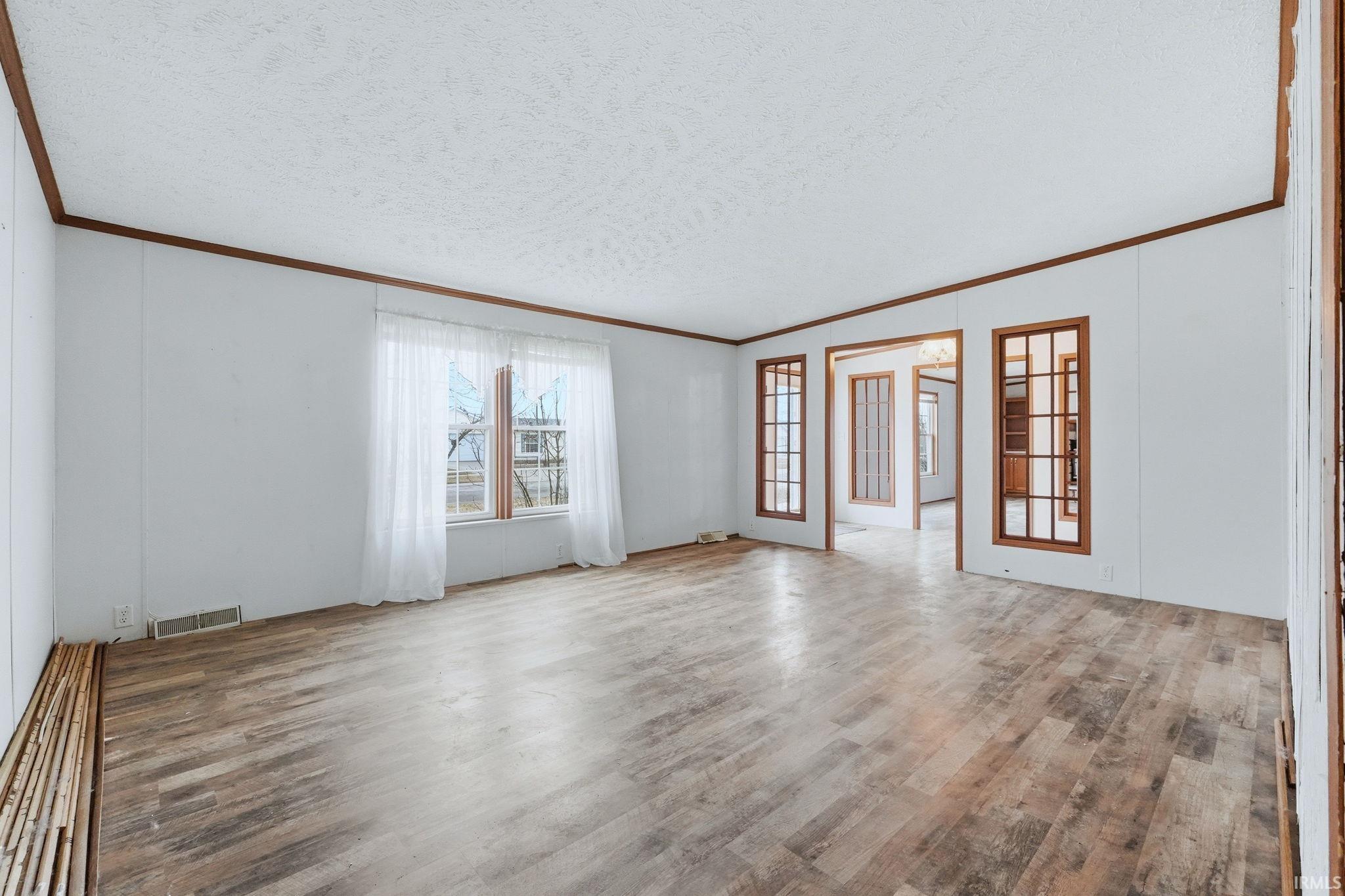 Spare room with light wood-style floors, ornamental molding, and a textured ceiling