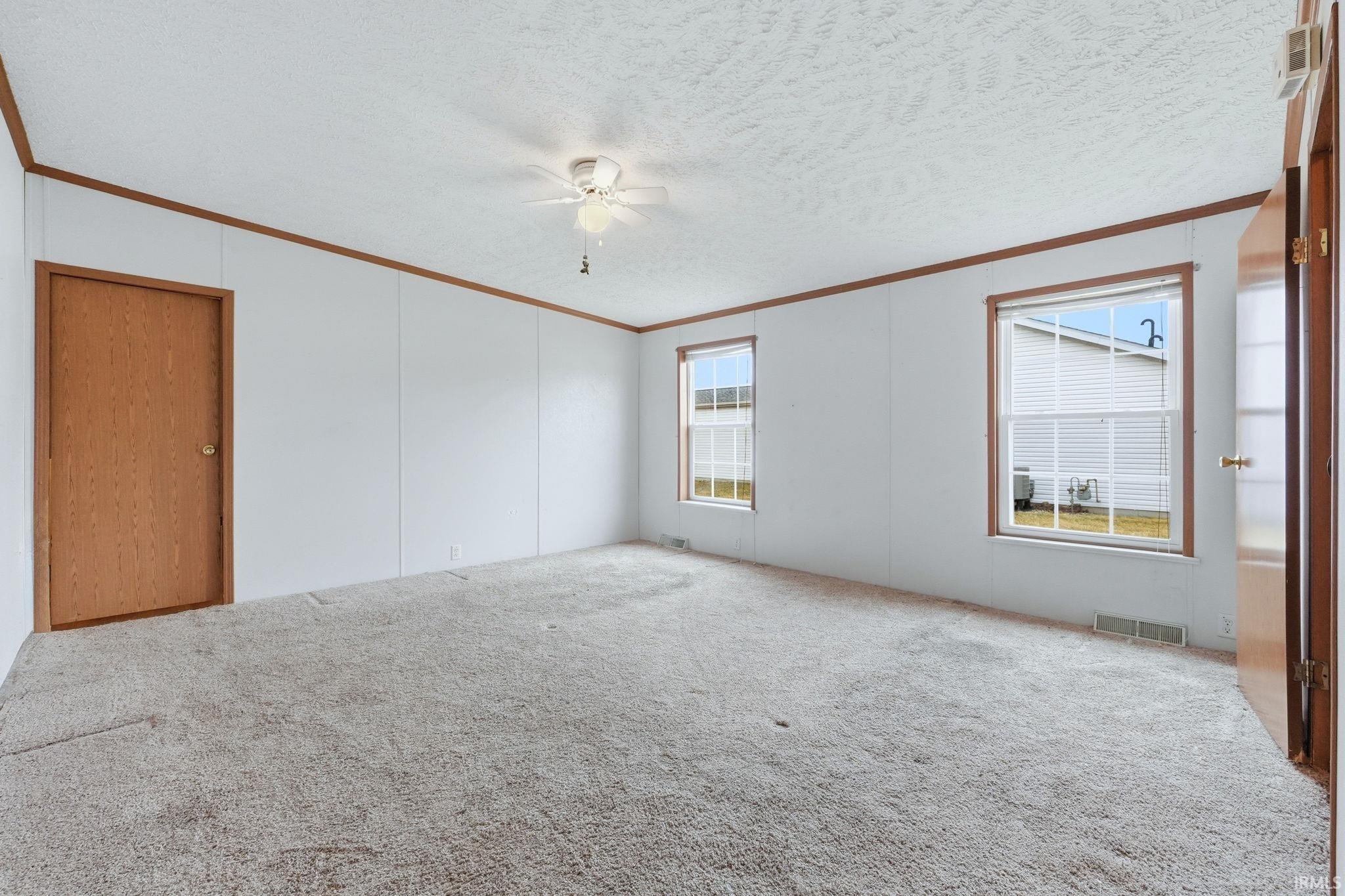 Spare room featuring carpet flooring, a textured ceiling, a ceiling fan, and ornamental molding
