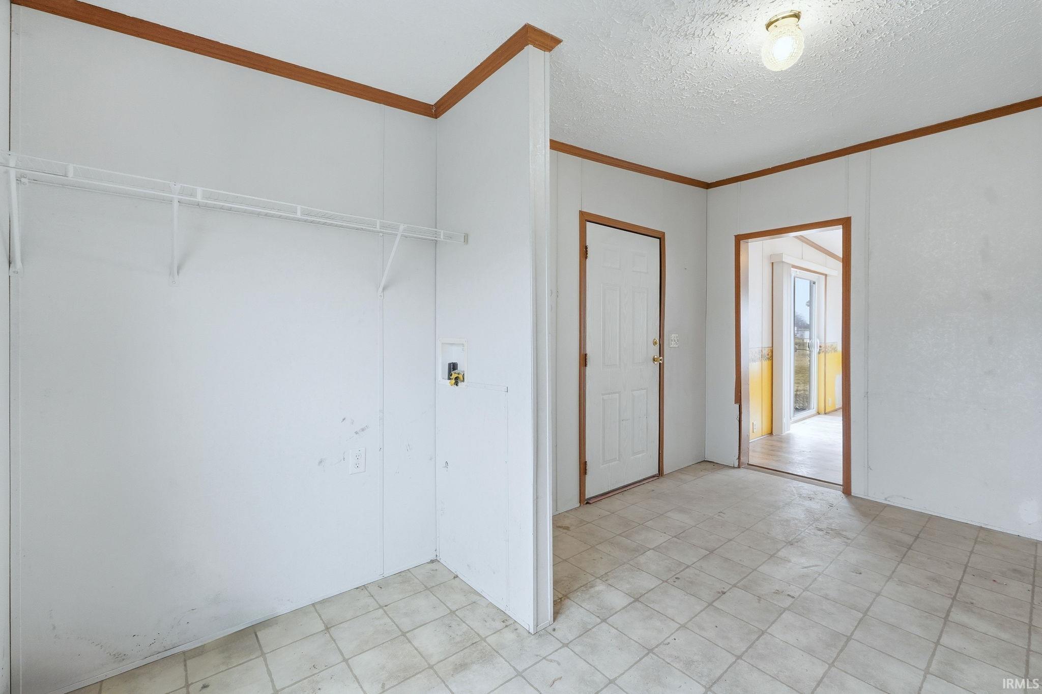 Laundry room with a textured ceiling, washer hookup, and ornamental molding