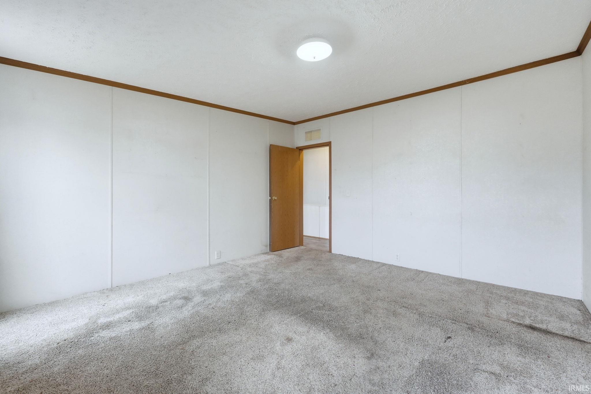 Carpeted spare room with crown molding