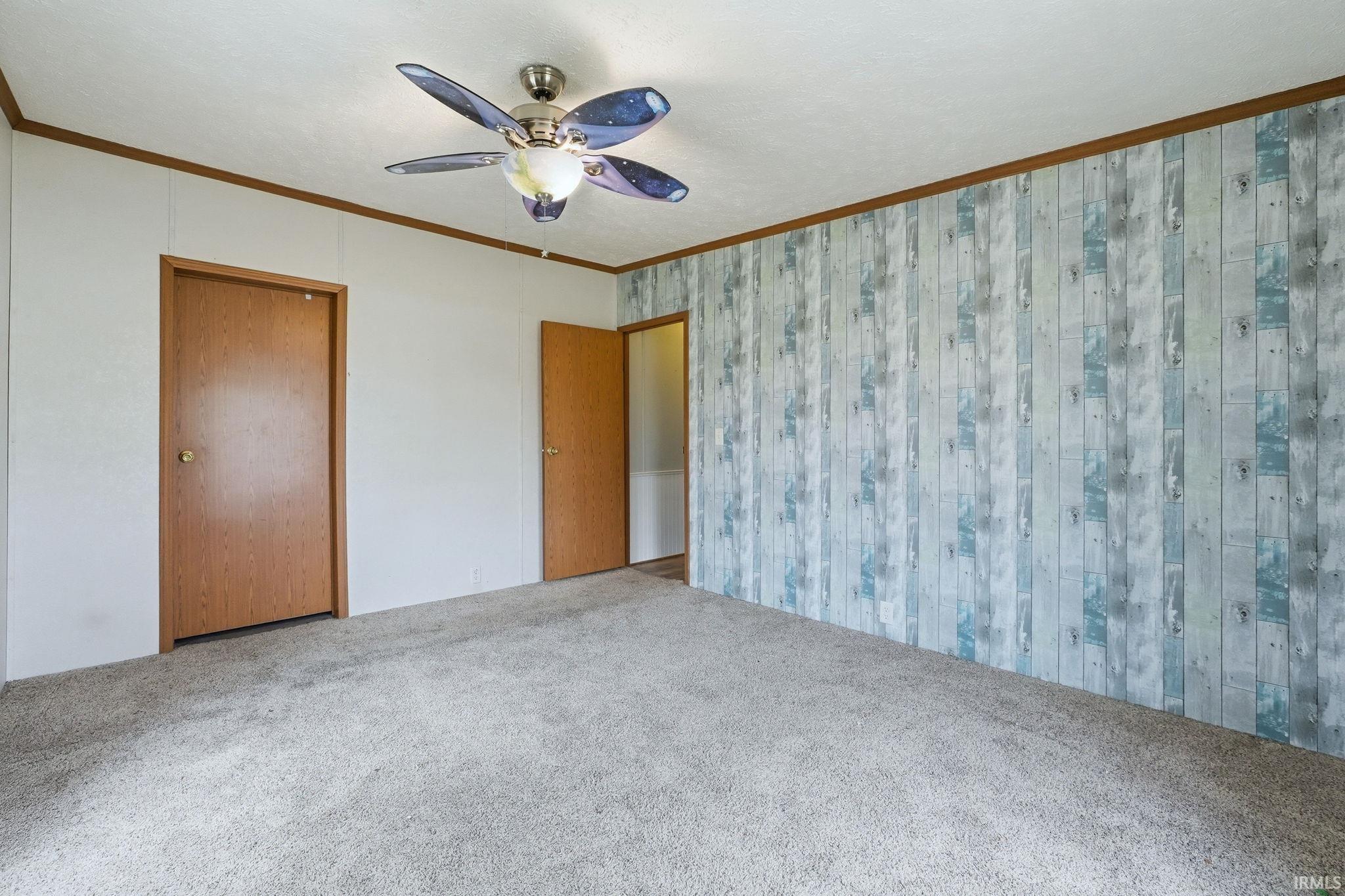 Unfurnished bedroom featuring carpet, a ceiling fan, and crown molding