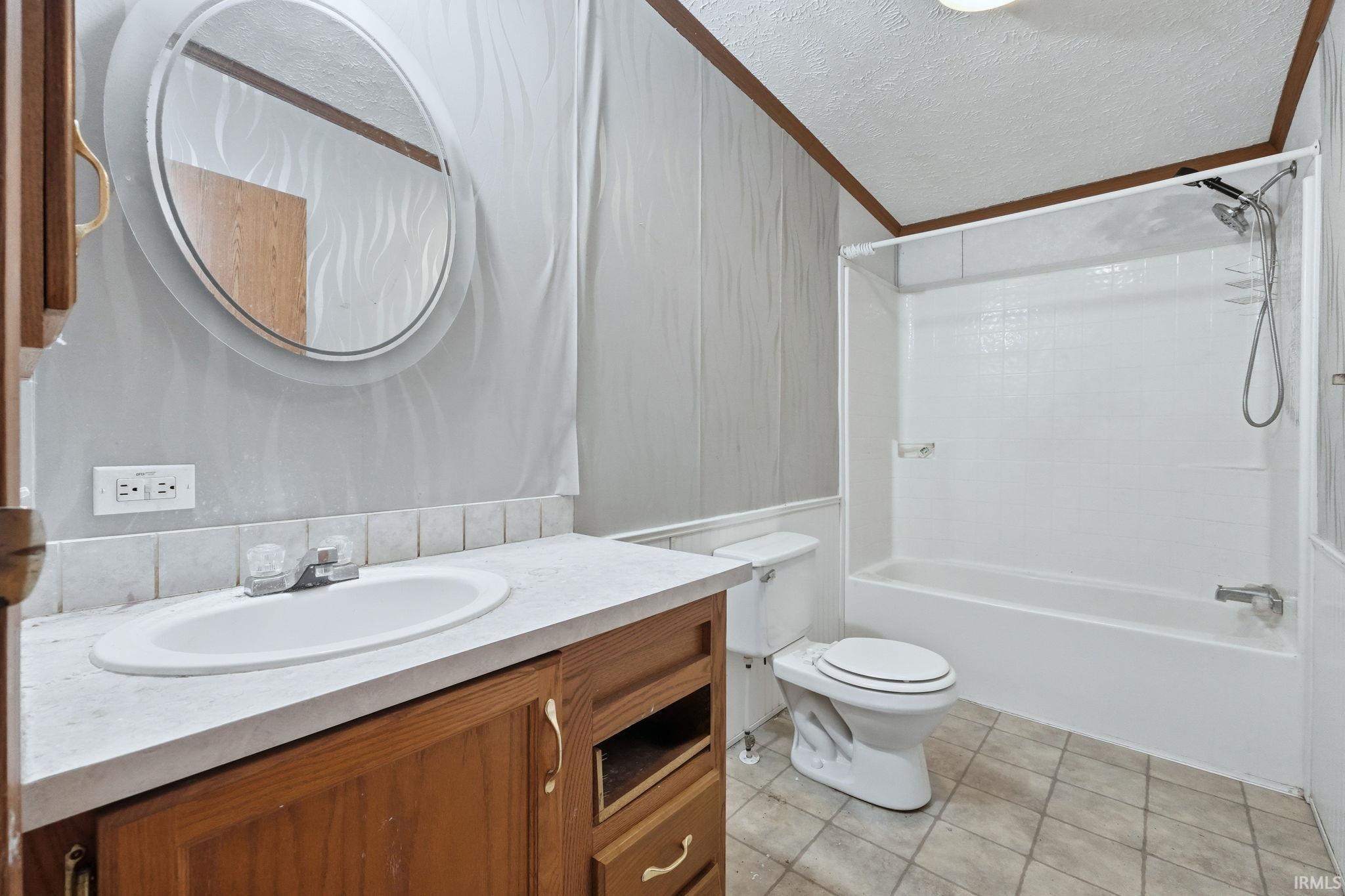 Bathroom featuring a textured ceiling, vanity, shower / bathtub combination, and light tile patterned floors