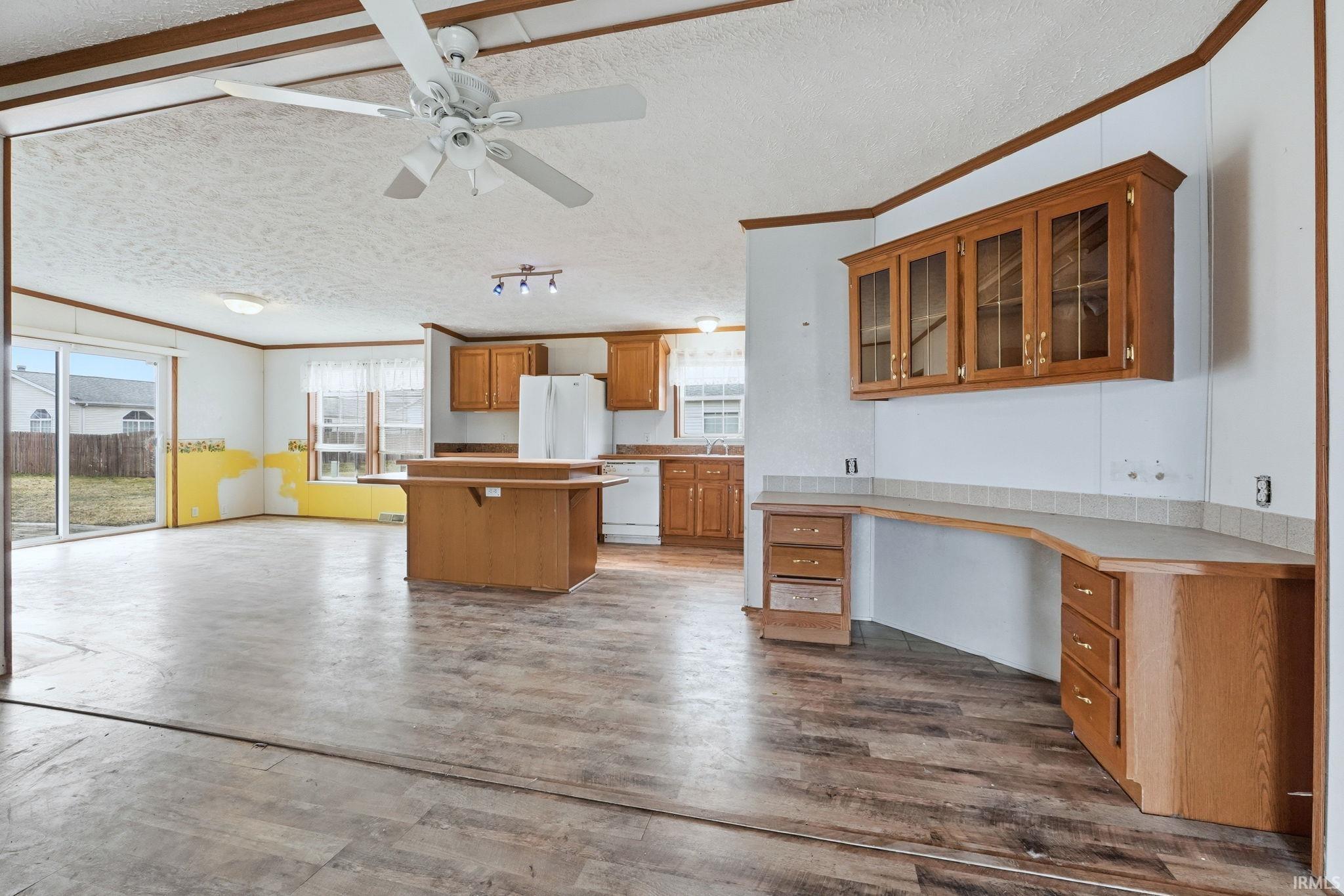 Kitchen featuring ornamental molding, light countertops, wood finish cabinetry, a ceiling fan, and white appliances