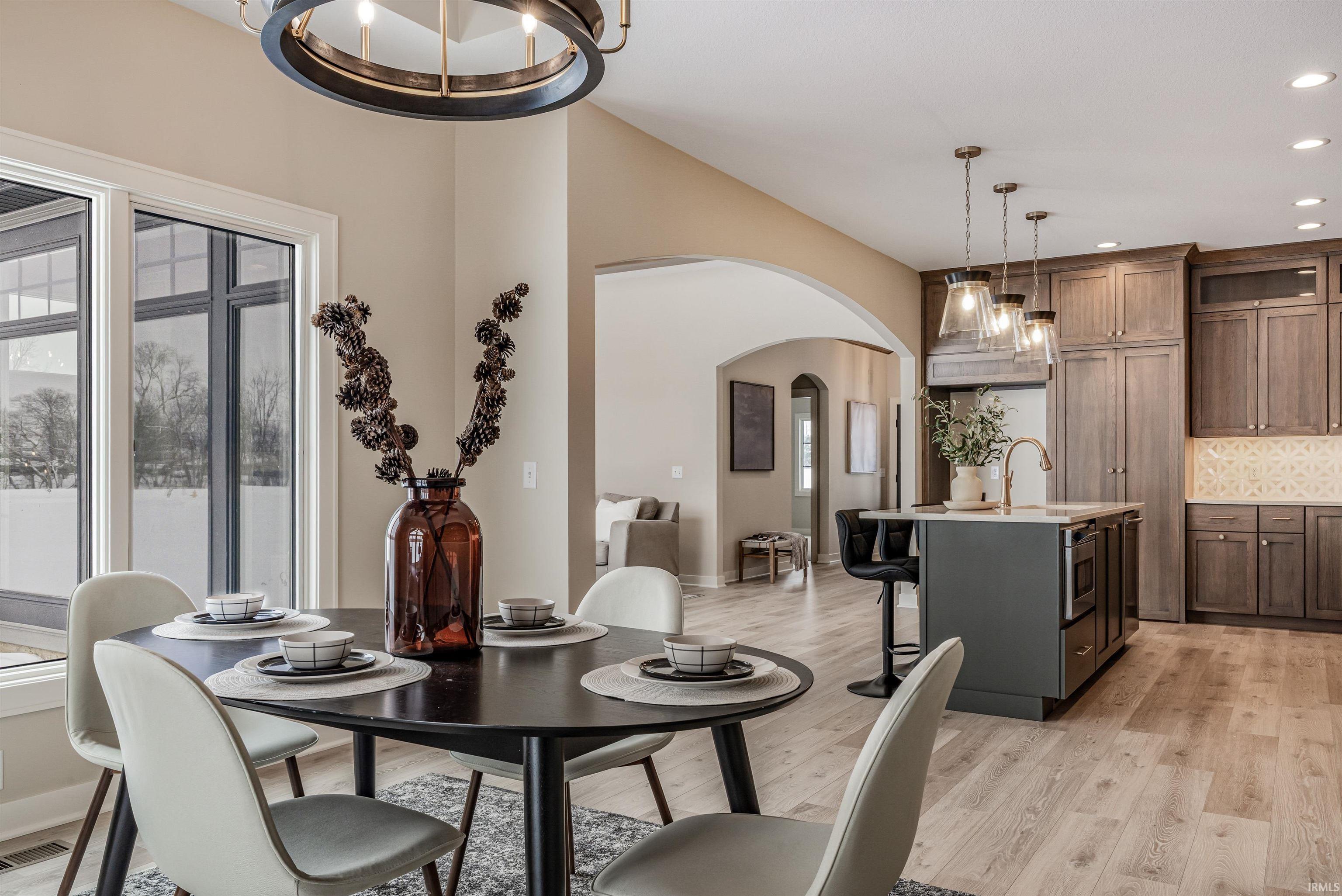 Dining space with arched walkways, a chandelier, light wood-type flooring, and recessed lighting