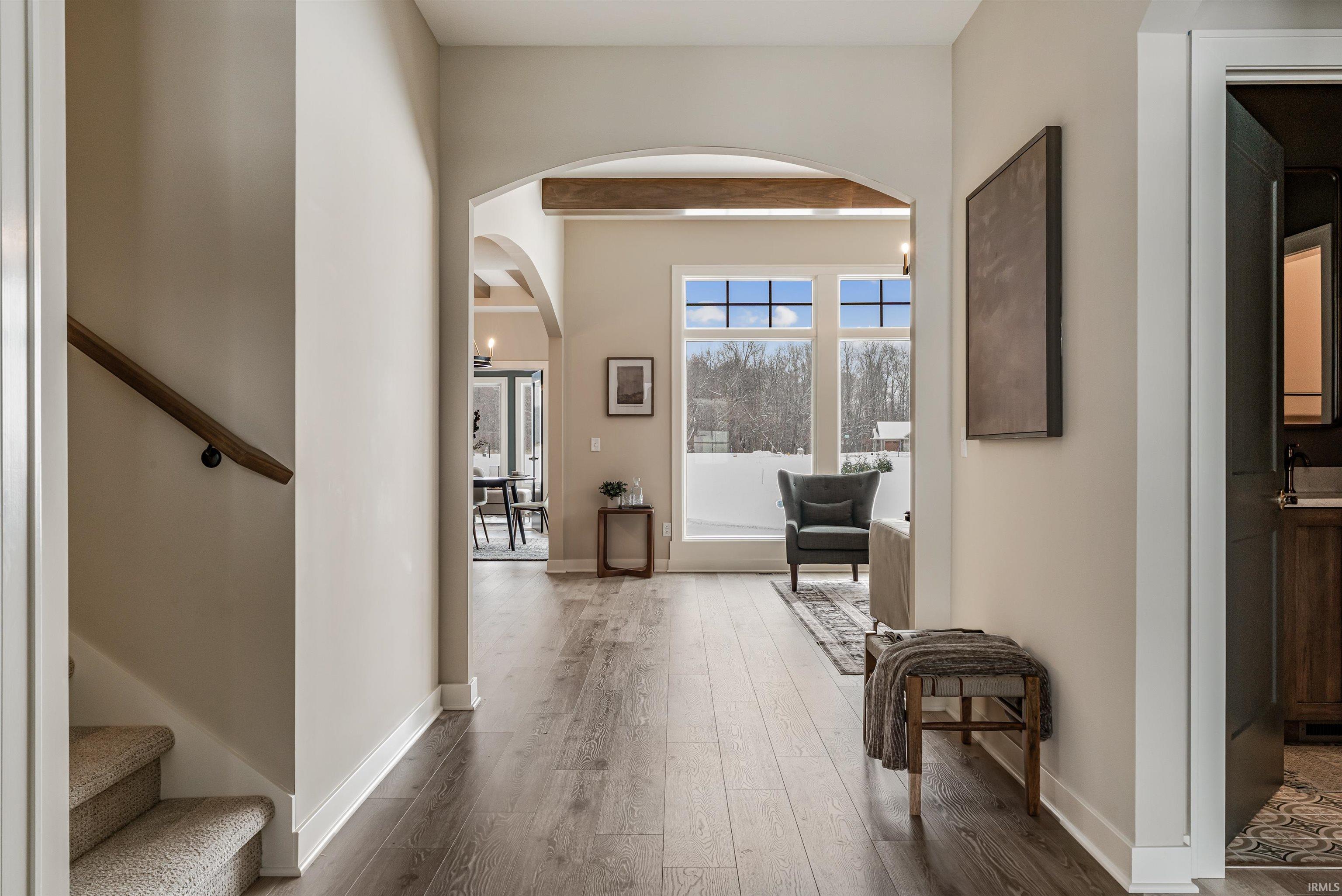 Hallway with stairway, hardwood / wood-style floors, beam ceiling, and arched walkways
