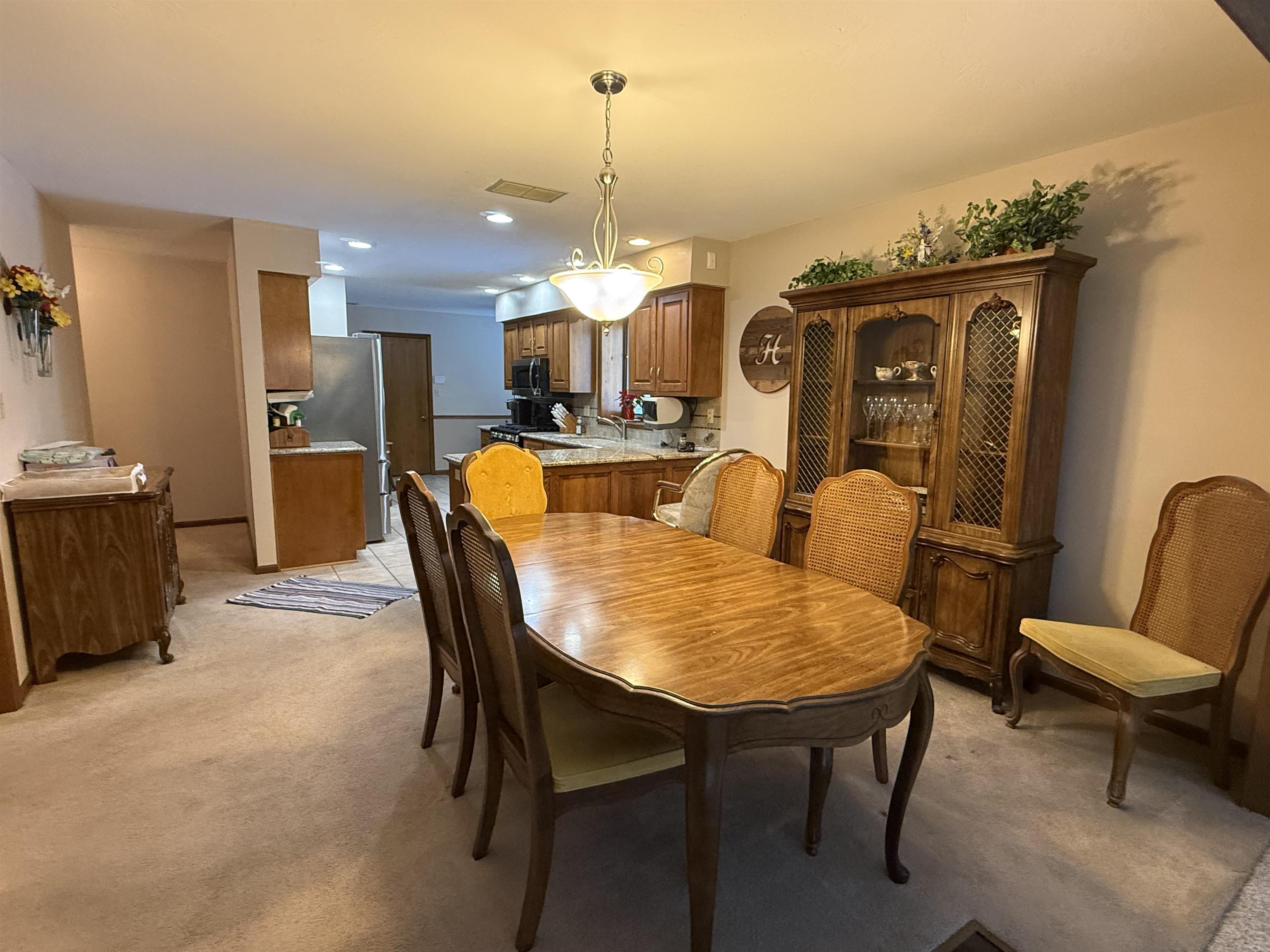 Dining area with light colored carpet and recessed lighting