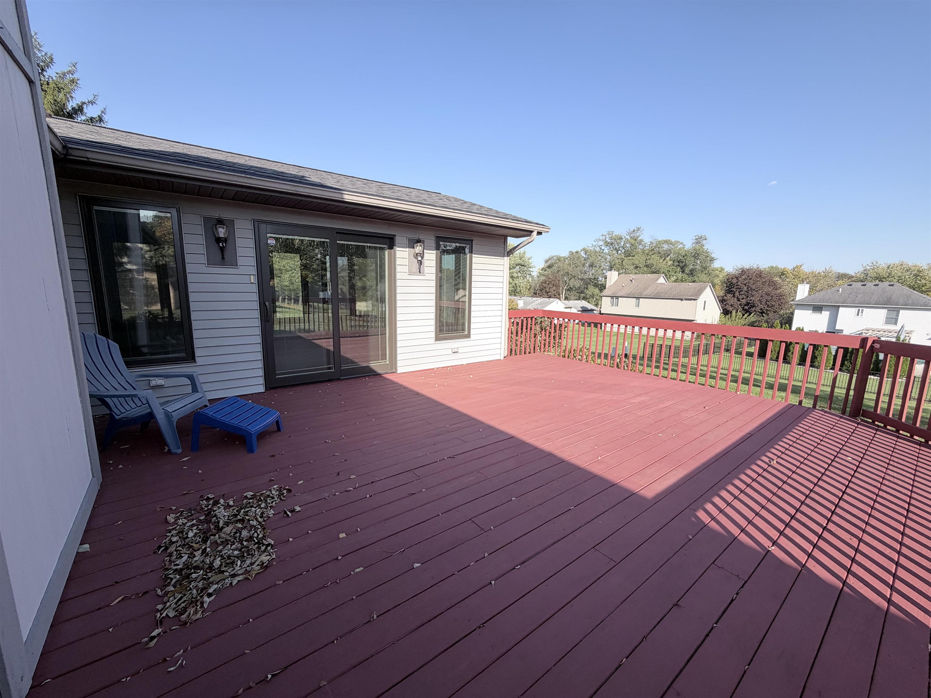 Expansive elevated wood deck featuring a railing and sliding glass door access