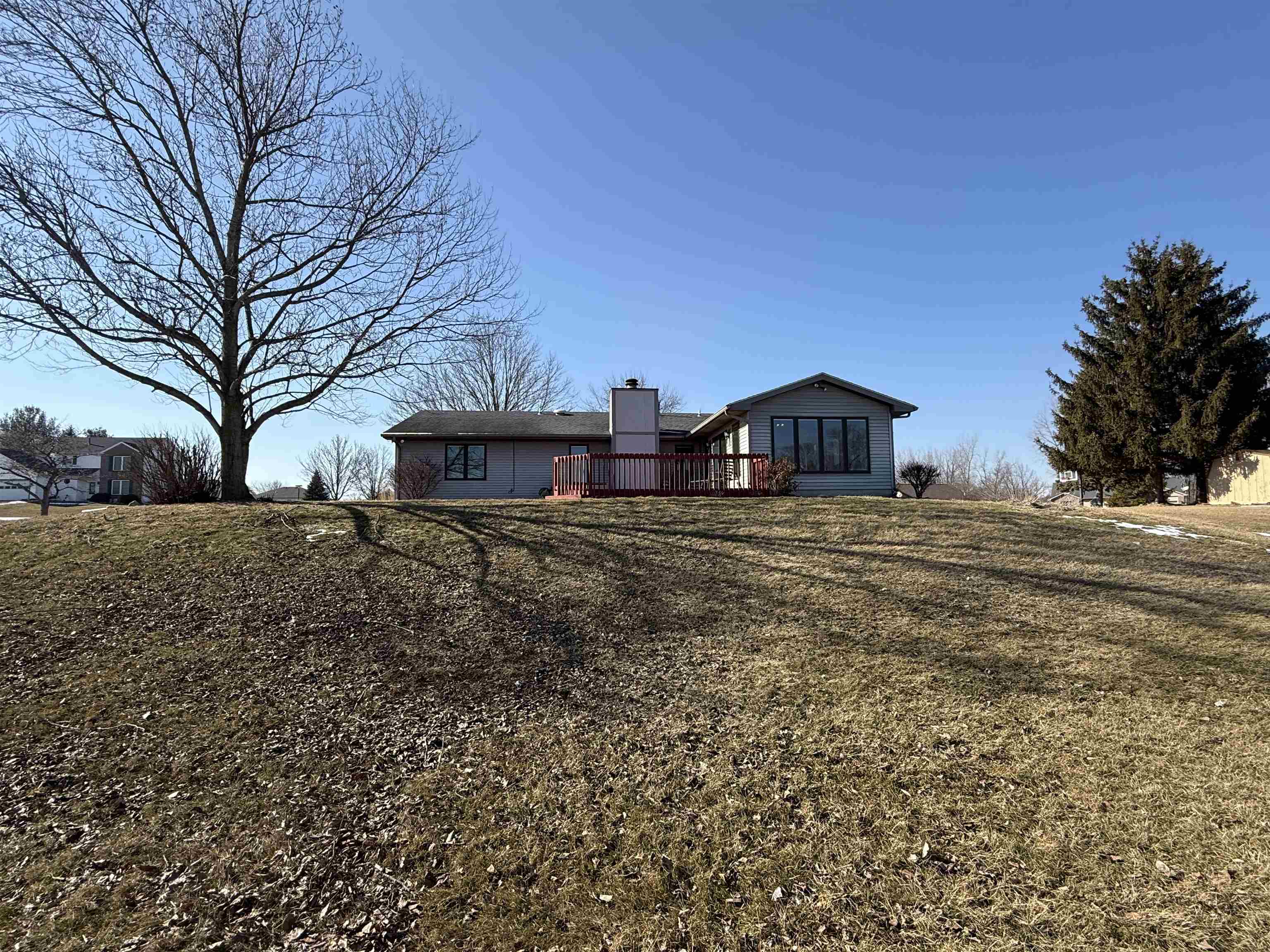 Back of house with a chimney, a yard, and a deck