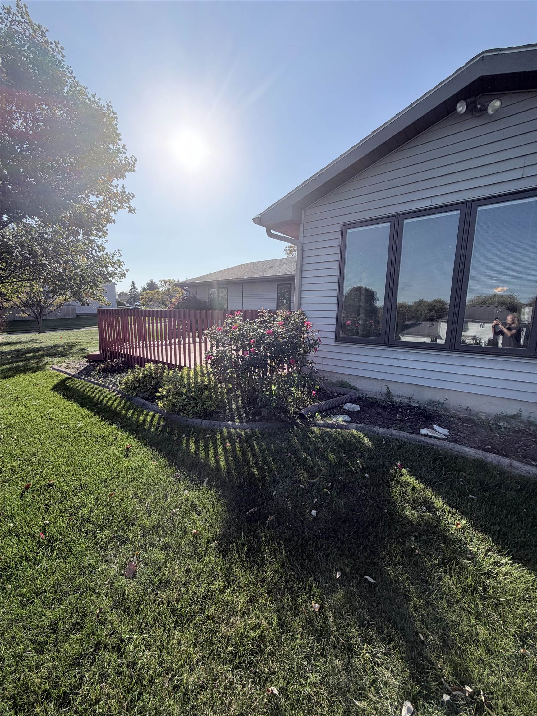 Exterior featuring horizontal siding, expansive rear deck with balustrades, large multi-pane windows, and landscaped garden beds with stone edging