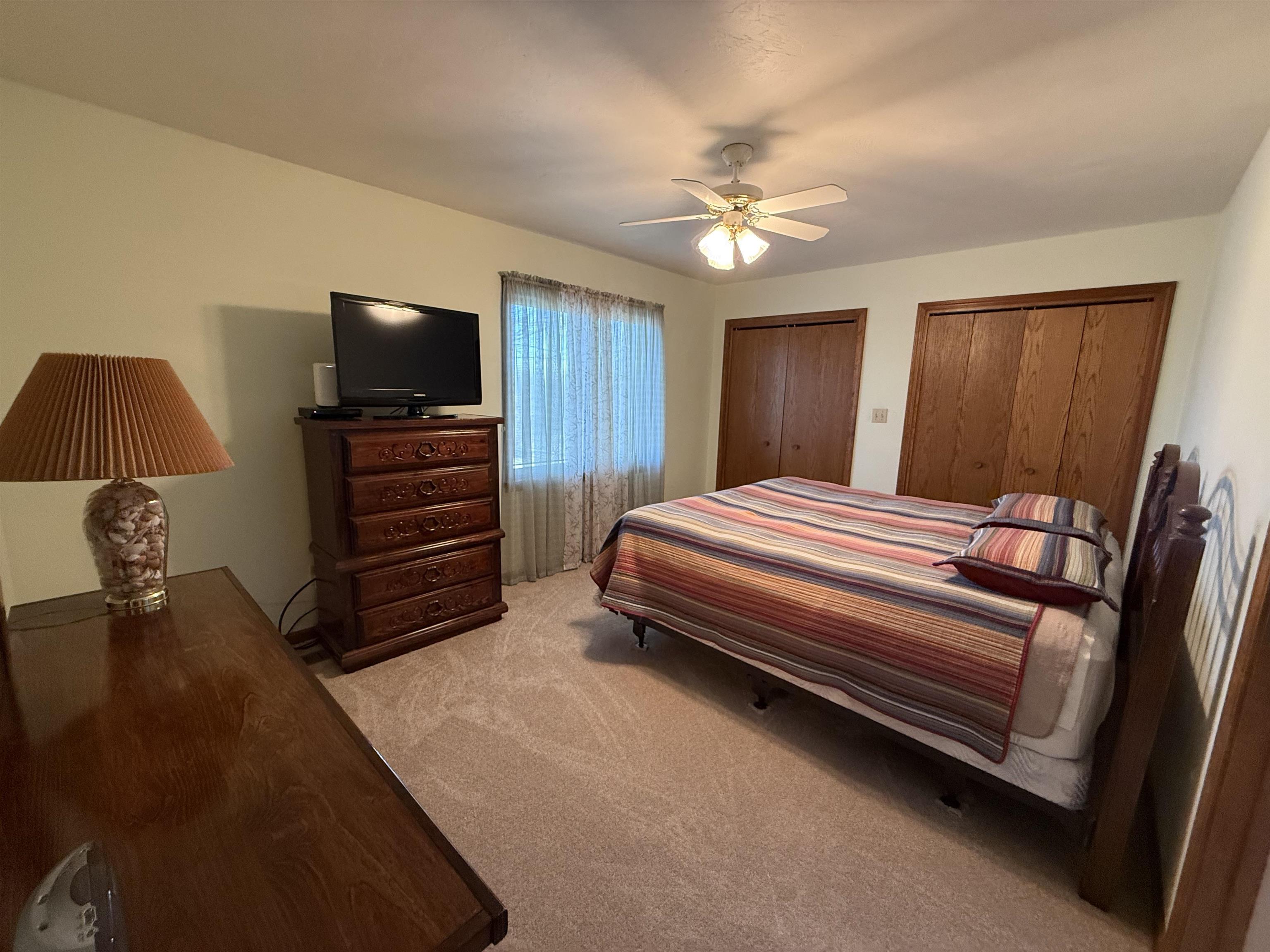 Bedroom featuring two closets, ceiling fan, and light carpet