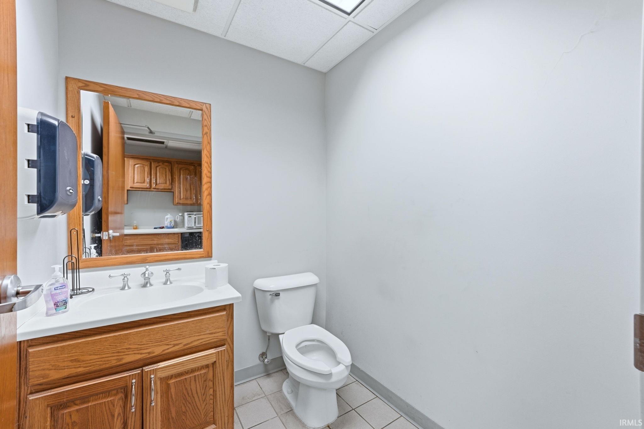 Bathroom with vanity, light tile patterned flooring, and a drop ceiling