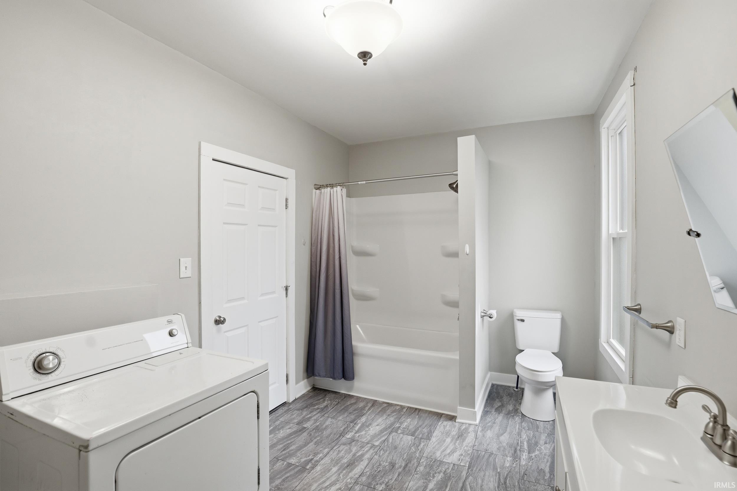 Bathroom with washer / clothes dryer, vanity, and shower / bath combo with shower curtain