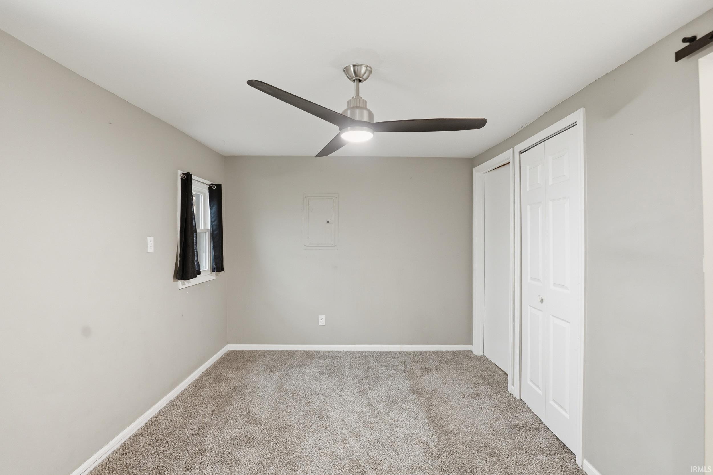 Unfurnished bedroom with light colored carpet, a closet, ceiling fan, and electric panel