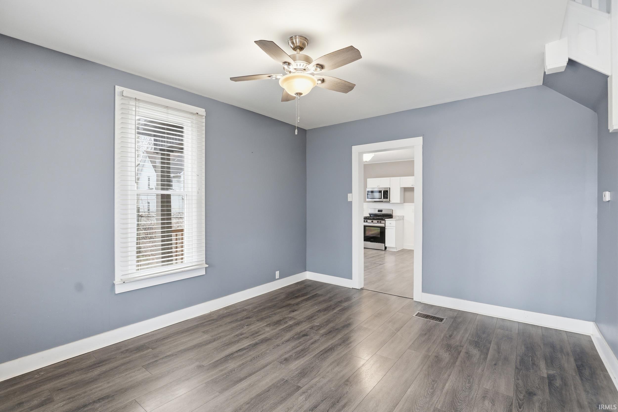 Unfurnished room featuring dark wood-style floors and a ceiling fan